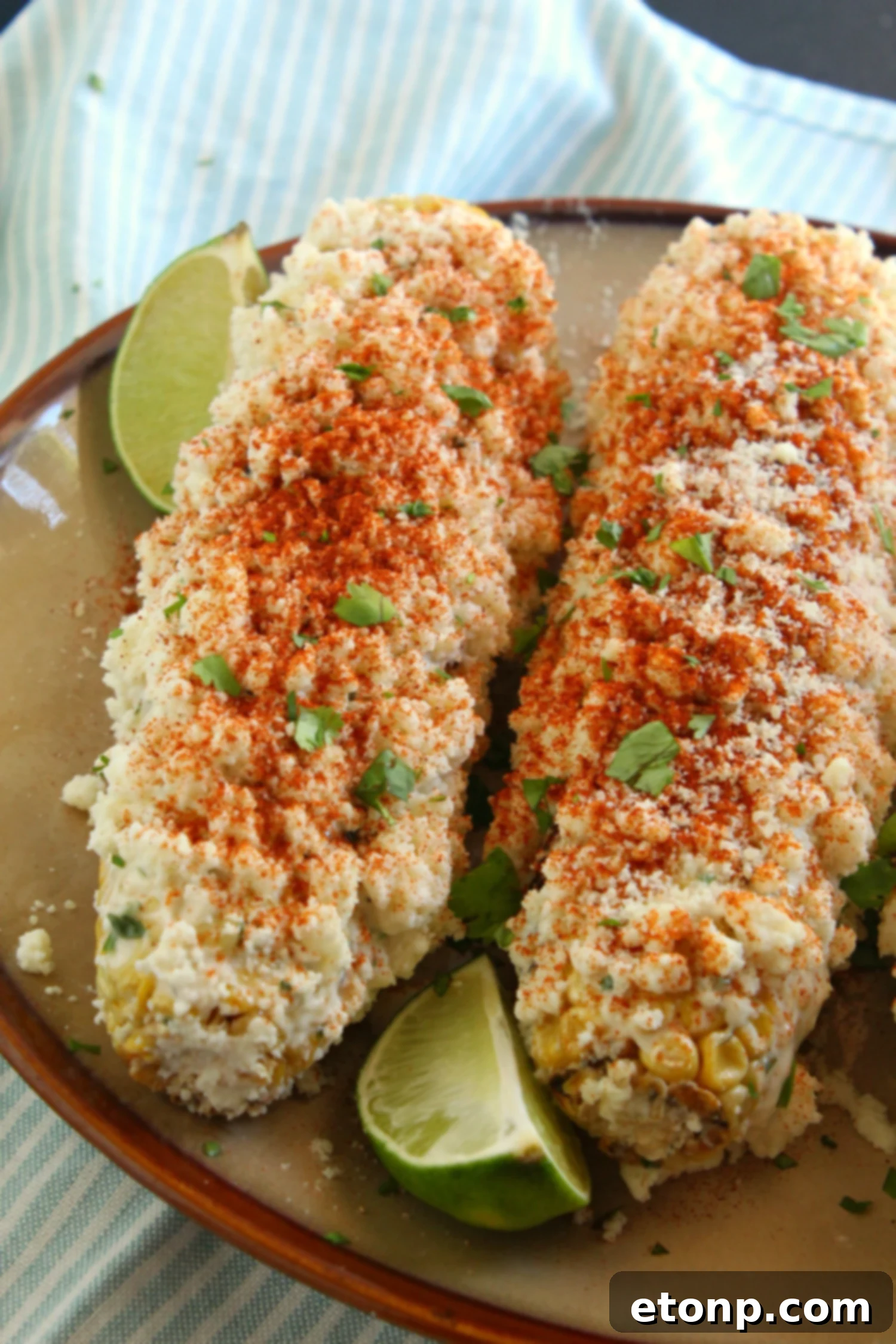 Grilled Mexican Street Corn being coated with sauce