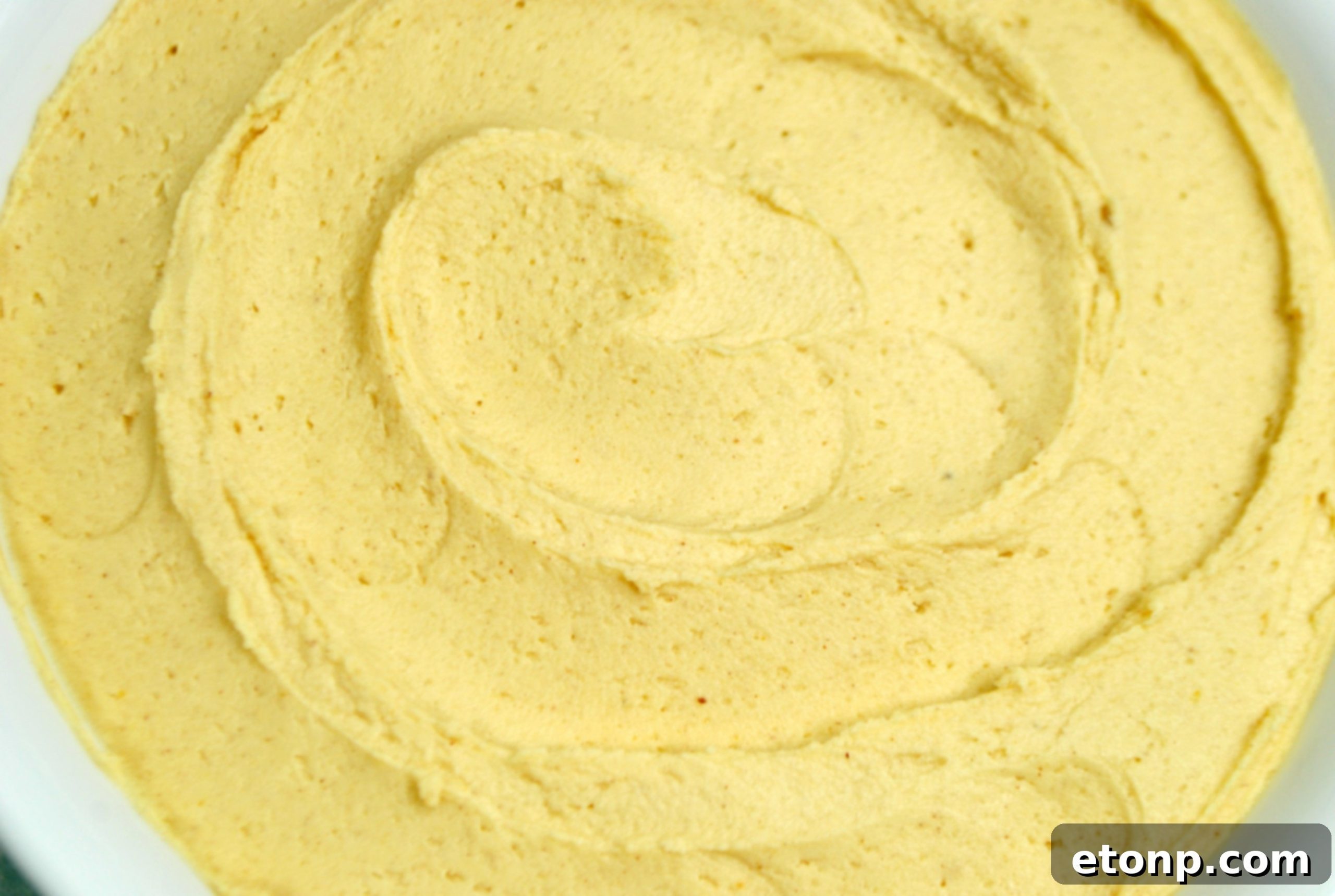 A beautifully frosted cupcake with a swirl of homemade peanut butter frosting, garnished with a sprinkle of peanuts.