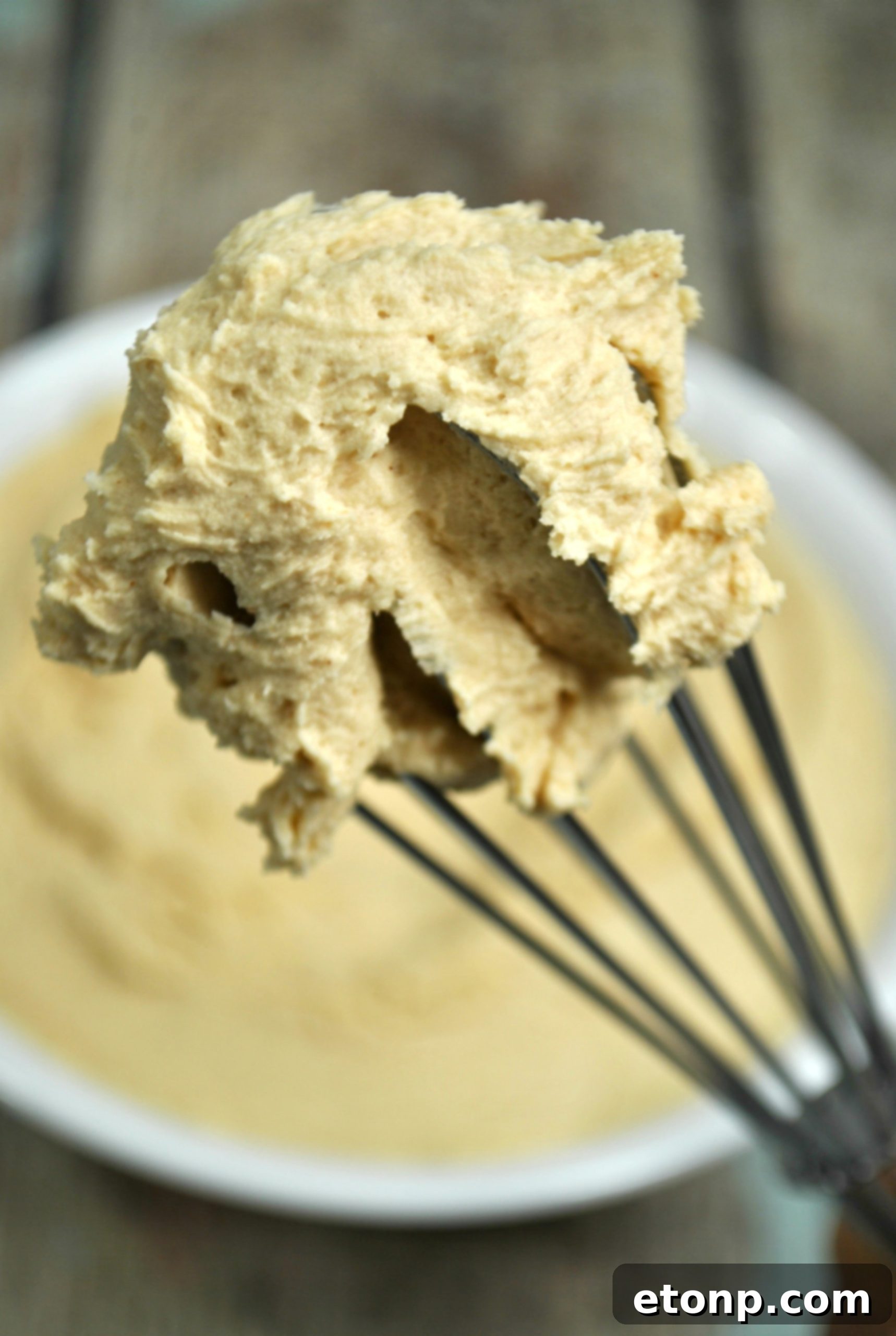 Two hands holding a frosted cupcake, showcasing the thick and smooth peanut butter frosting.