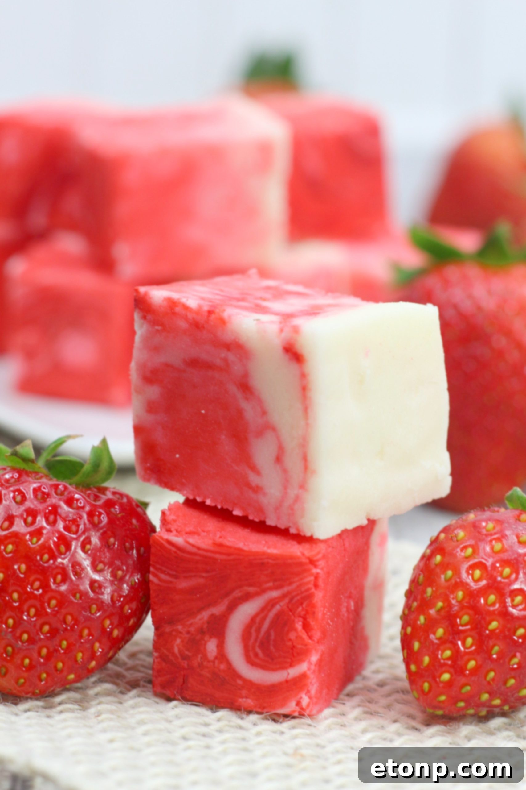 Close-up of a square of creamy pink and white strawberry swirl fudge