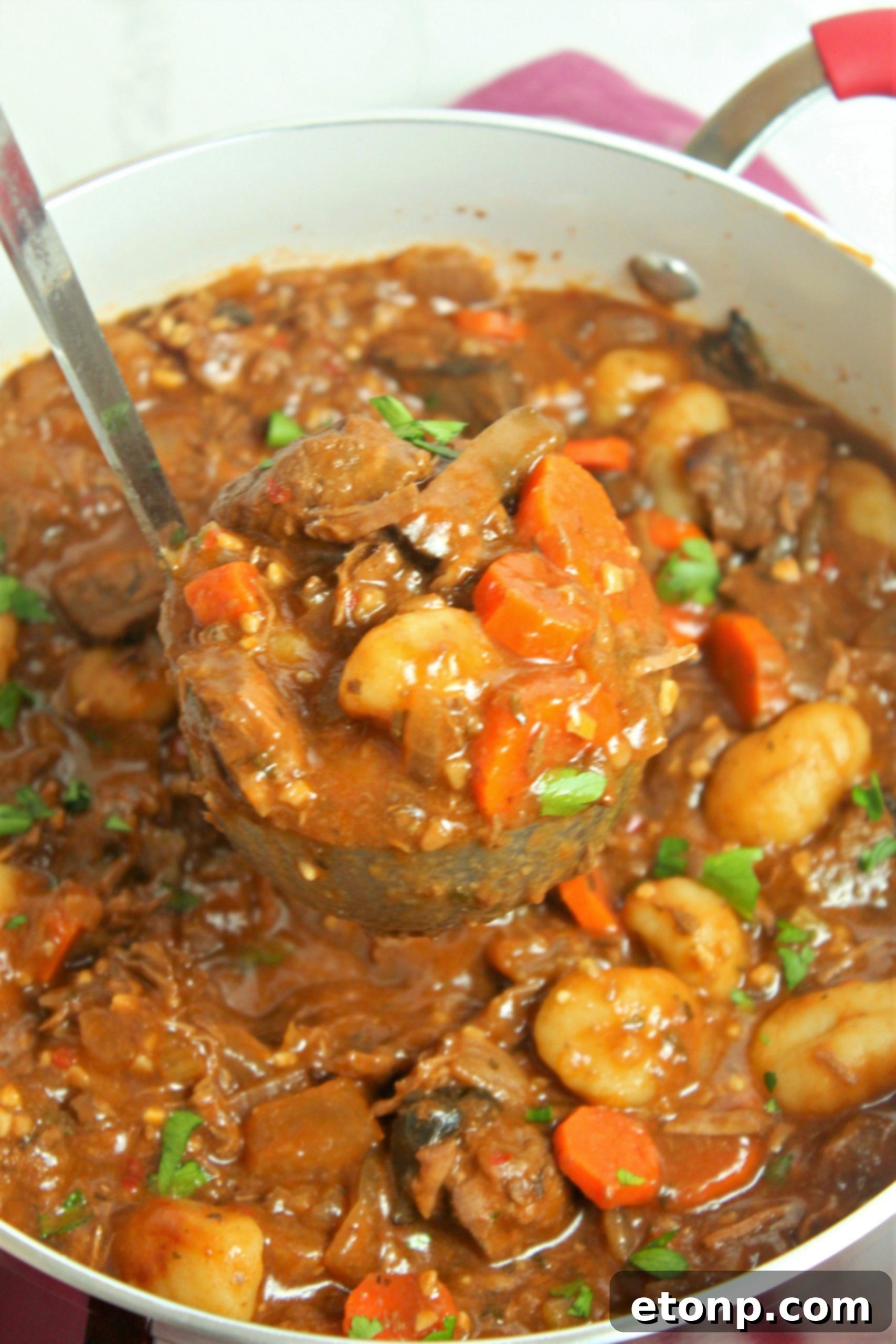 A large pot of chunky beef and gnocchi soup simmering on the stovetop, demonstrating the slow-cooking process.