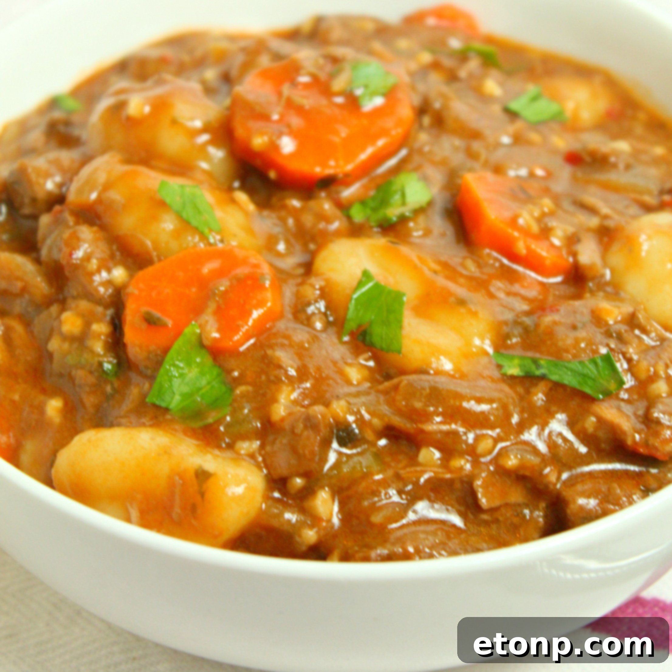 Individual servings of chunky beef and gnocchi soup portioned into containers for freezer storage, highlighting its meal prep convenience.