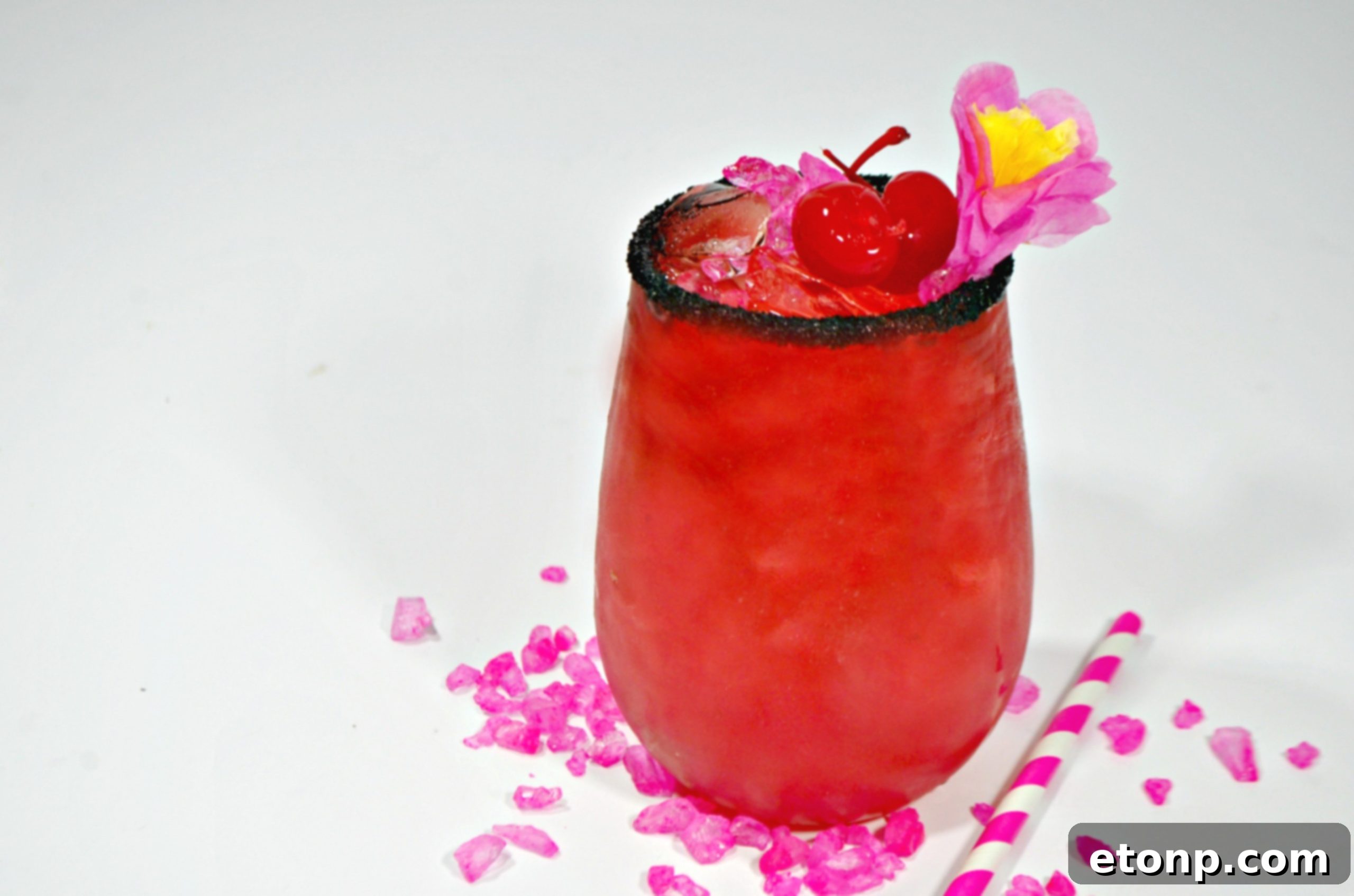Close-up of the Barbie cocktail, highlighting the vibrant pink liquid and the elegant black sprinkle rim.