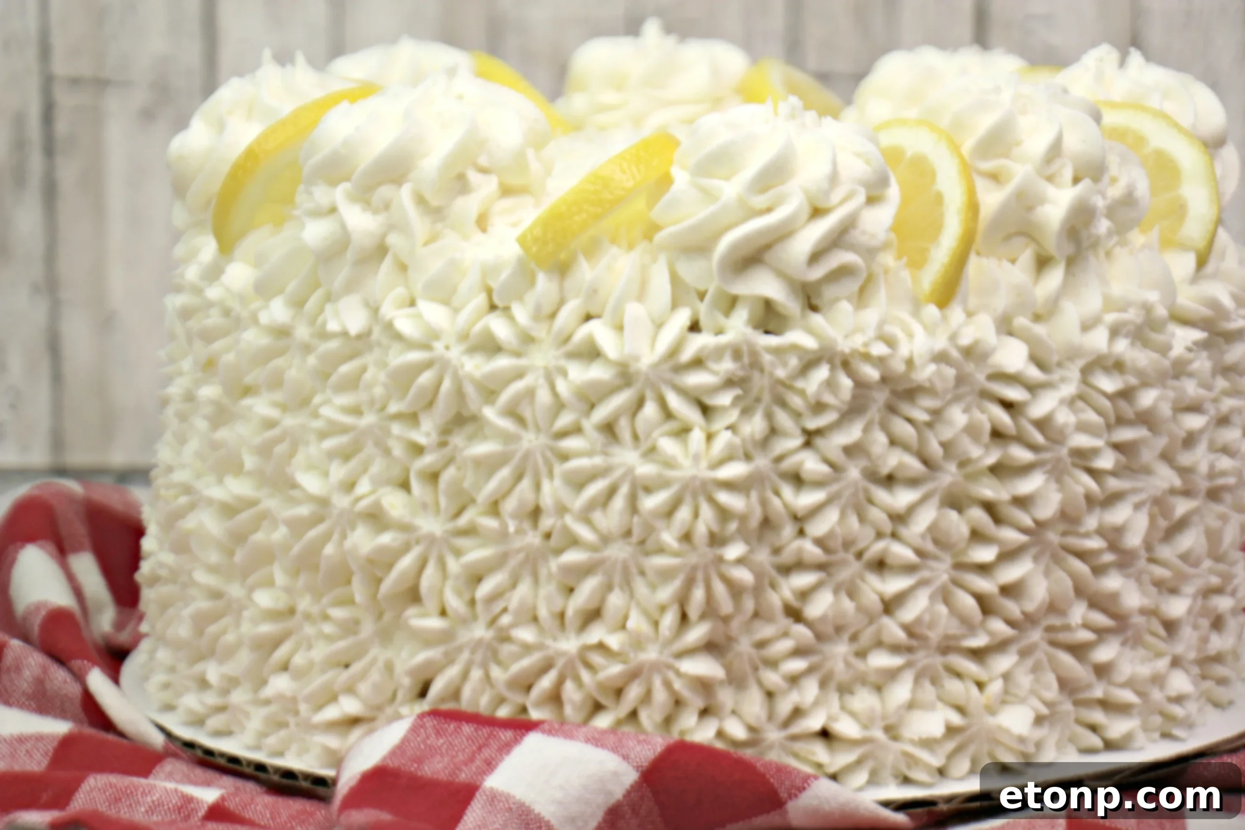 Another perspective of the Italian Lemon Drop Cake, highlighting the beautiful piping of the buttercream frosting and lemon garnish.