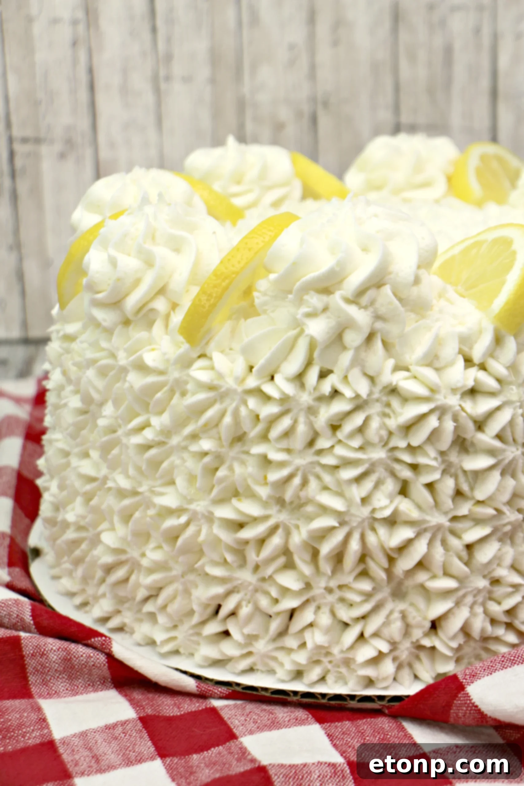 A top-down view of the Italian Lemon Drop Cake, featuring a generous amount of lemon buttercream and fresh lemon slices.