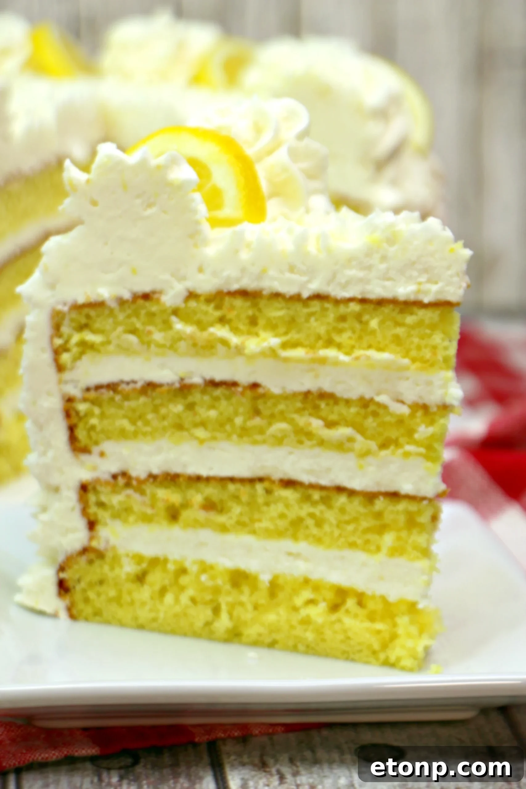 A close-up shot of the top of the Italian Lemon Drop Cake, highlighting the texture of the piped buttercream and the vibrant yellow lemon slices.