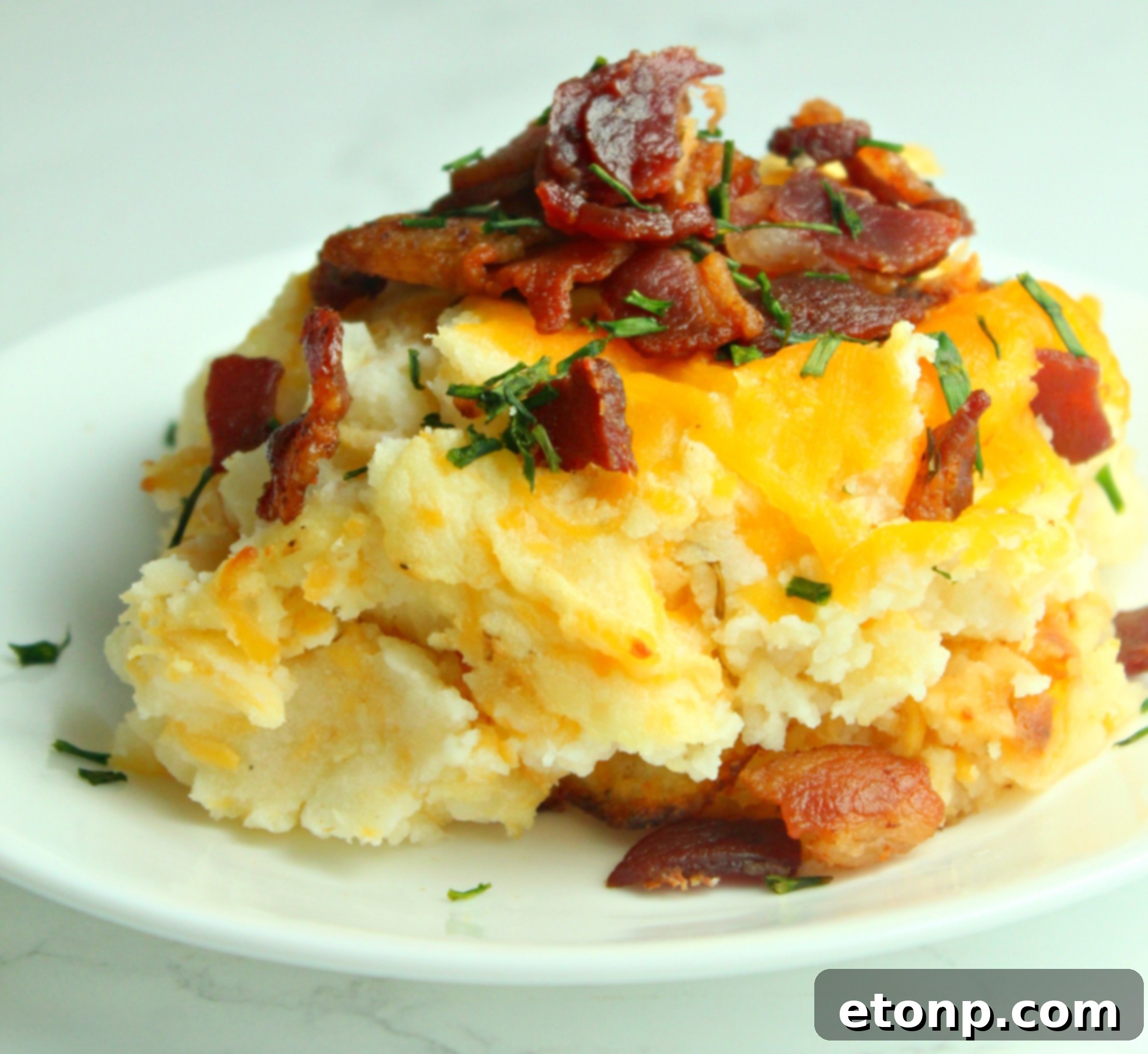 Ultimate Loaded Mashed Potato Casserole 7 Close-up of the golden-brown, cheesy topping of the casserole with visible bacon pieces.
