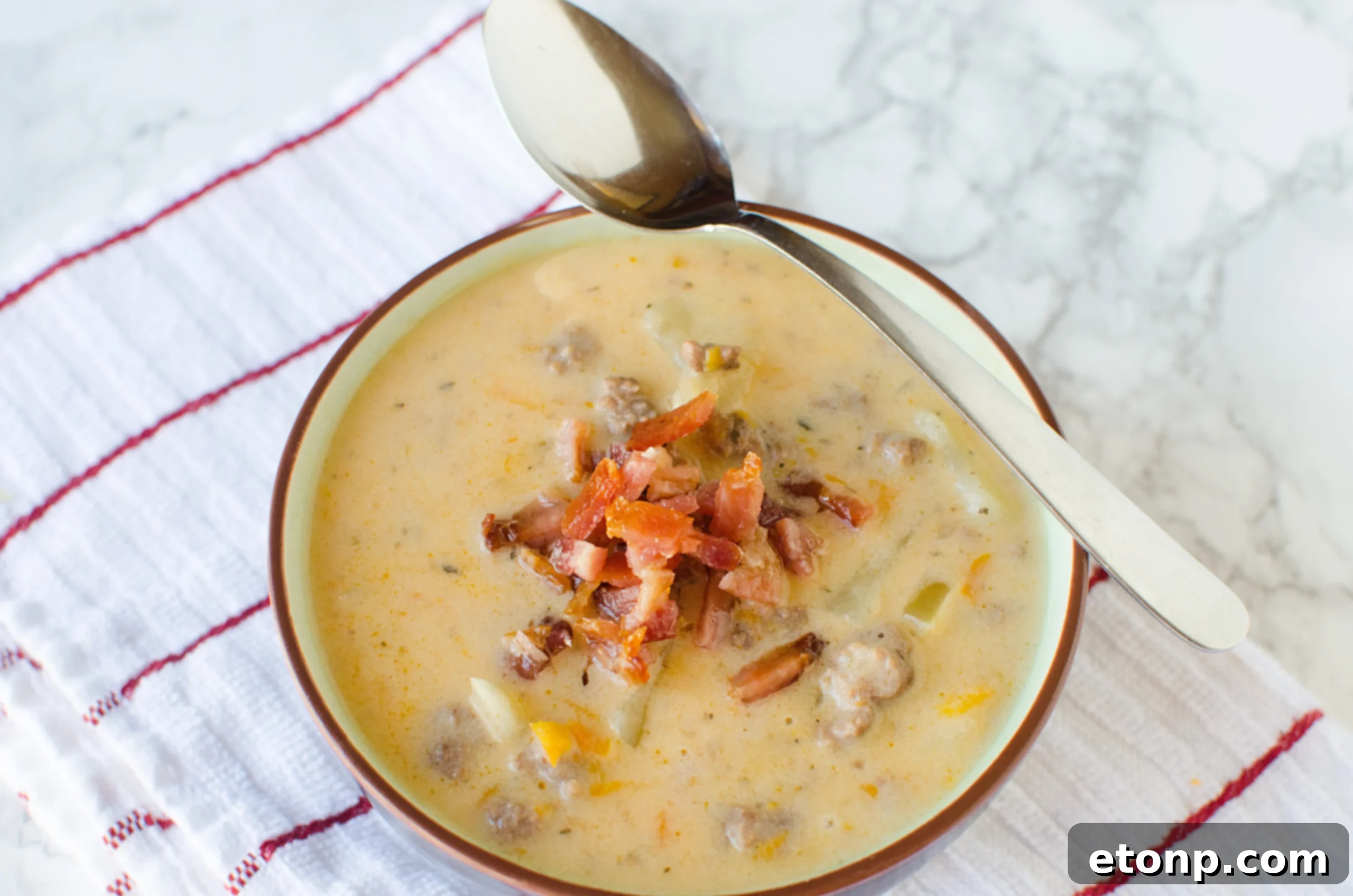 A close-up shot of Slow Cooker Cheeseburger Soup, showcasing its rich texture and chunks of beef and vegetables.