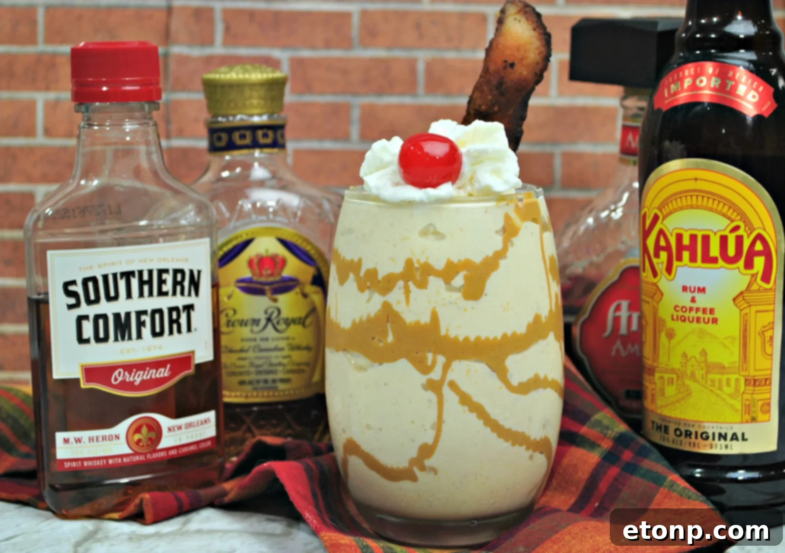 Dirty Elvis Cocktail 3 Two Dirty Elvis Cocktails in tall glasses, with whipped cream and a cherry on top. One glass also features a piece of bacon as garnish. The background is softly blurred, highlighting the drinks.