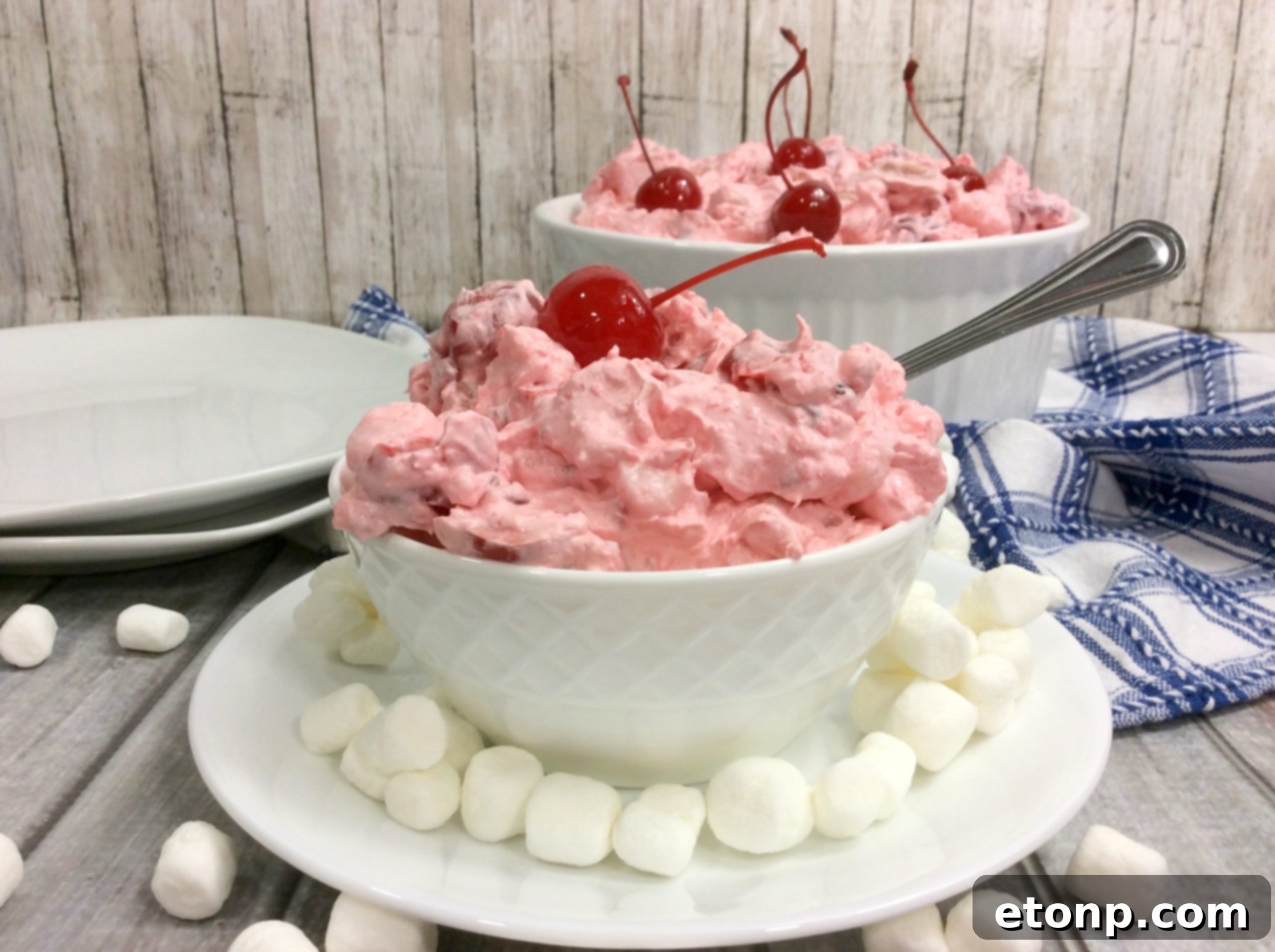 Individual serving of Cherry Fluff Salad in a small glass dish, garnished with a single cherry.