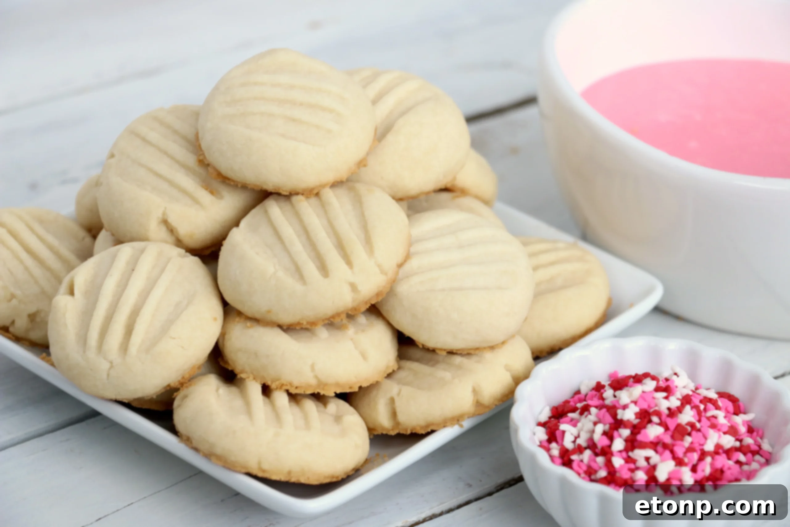 Velvet Vanilla Frosted Delights 4 Melt-Away Vanilla Frosted Cookies with festive pink icing and heart sprinkles for Valentine's Day.