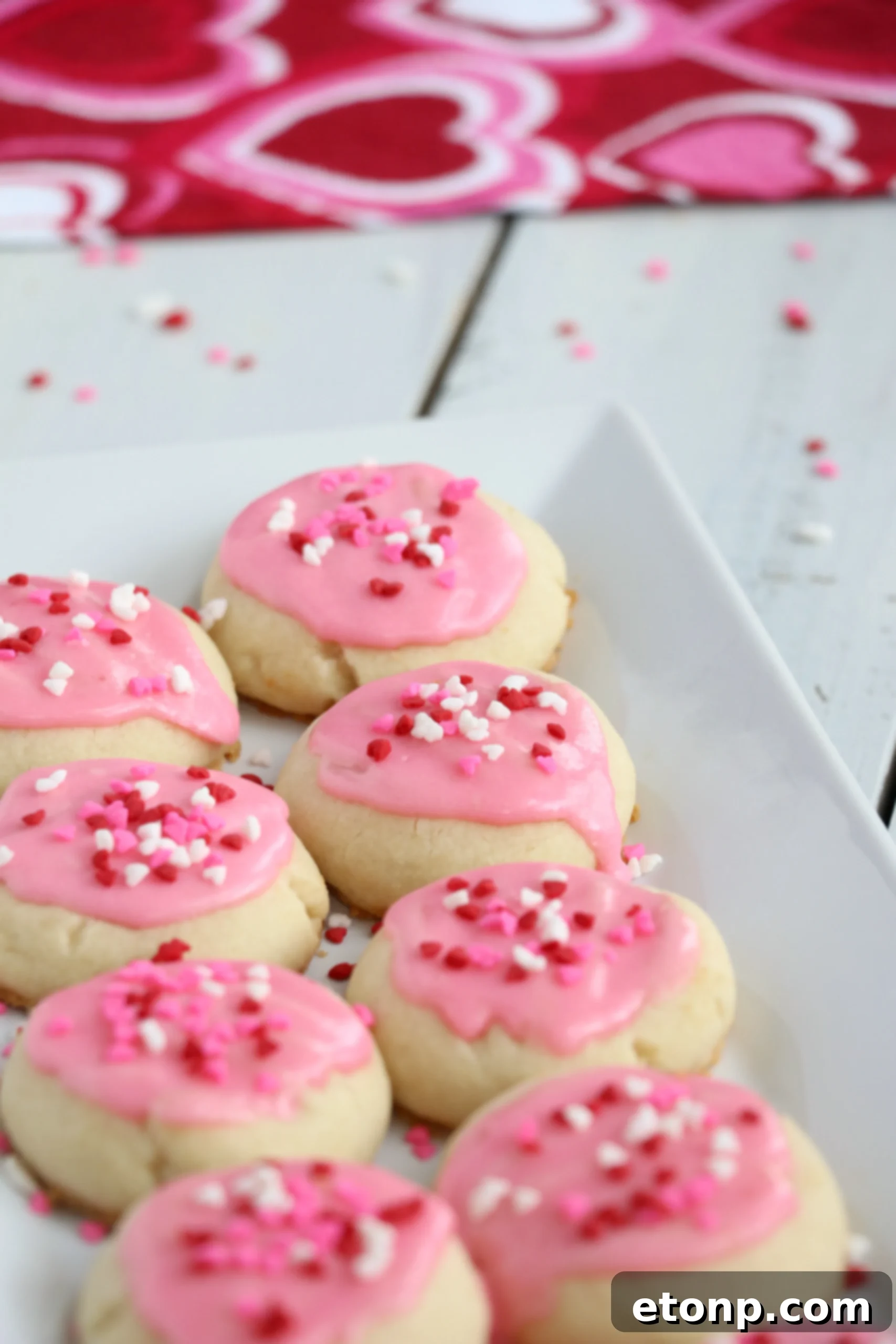 Velvet Vanilla Frosted Delights 9 A festive display of Melt-Away Vanilla Frosted Cookies with pink frosting and sprinkles, perfect for sharing.