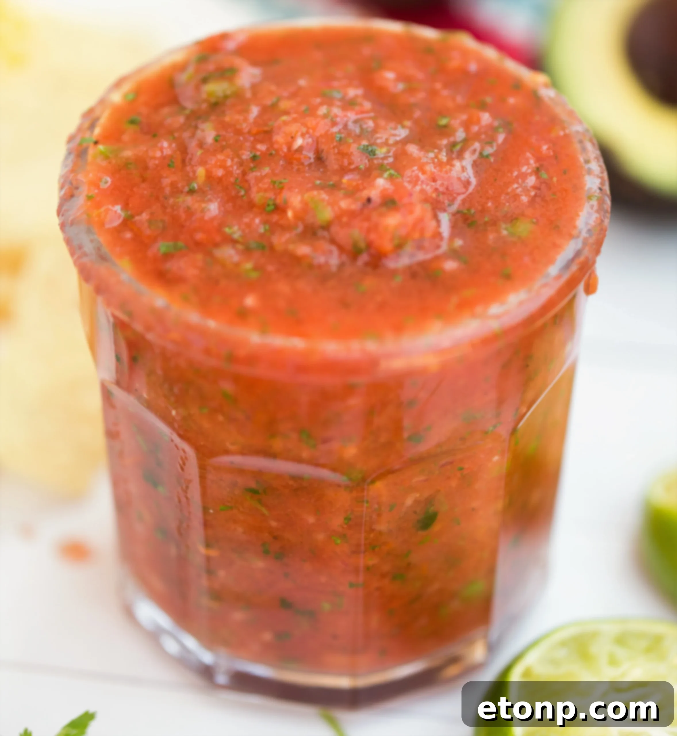 A vibrant bowl of freshly made restaurant-style salsa, garnished with cilantro, next to a pile of golden tortilla chips.