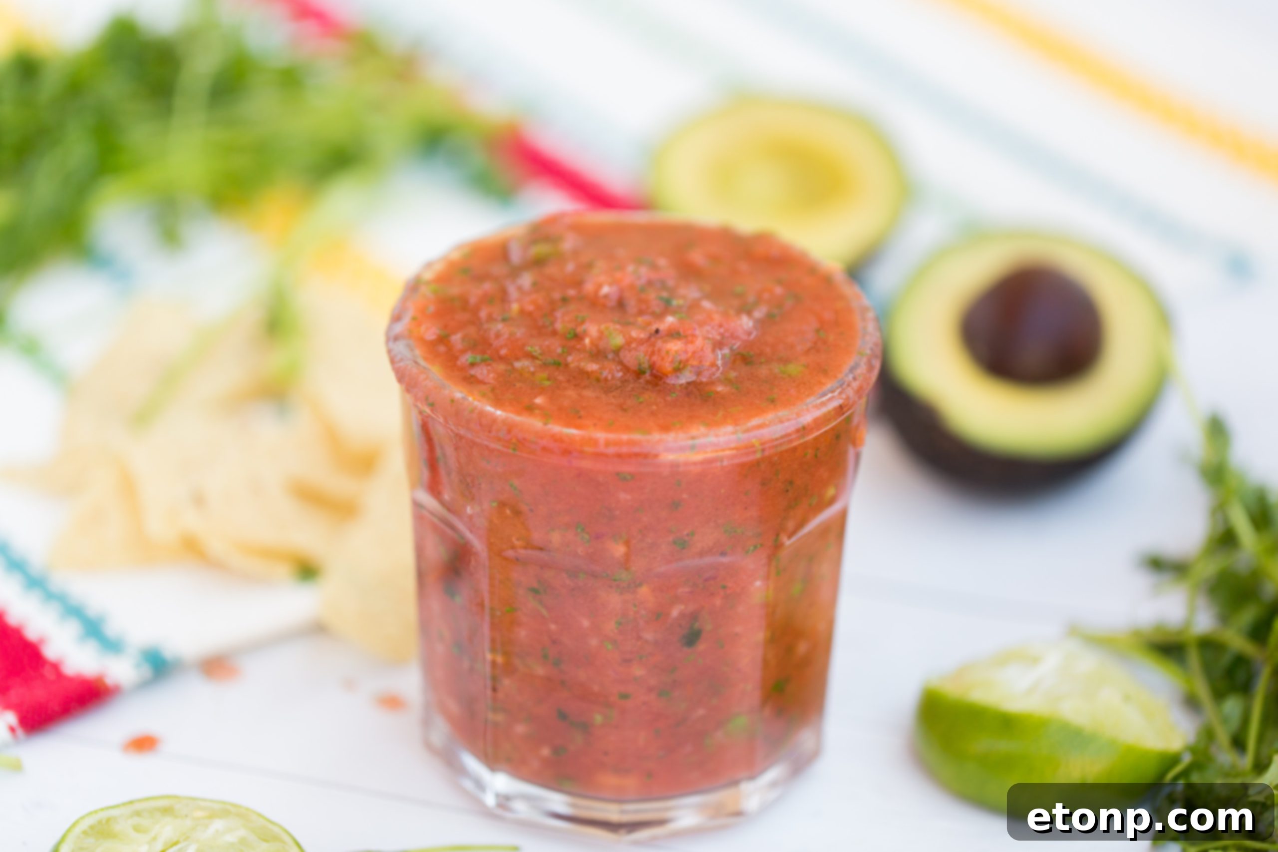 A large bag of classic tortilla chips sits invitingly beside a generously filled bowl of fresh homemade salsa, ready for an irresistible snack.