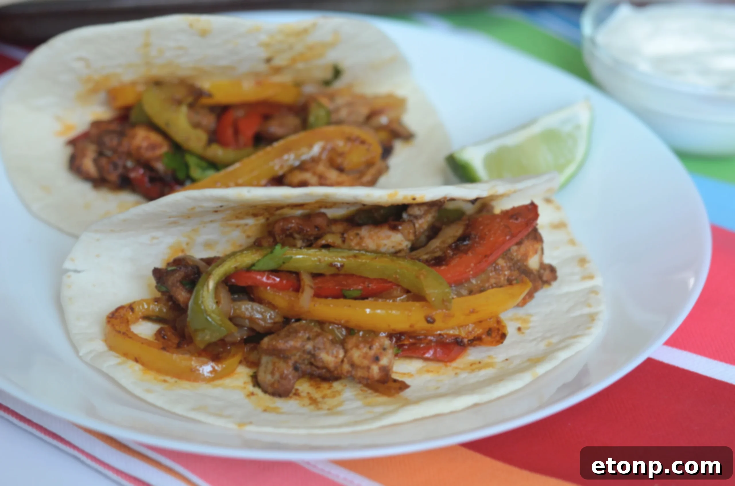 Sheet pan filled with vibrant, freshly cooked chicken fajitas, bell peppers, and onions, garnished with cilantro and lime.