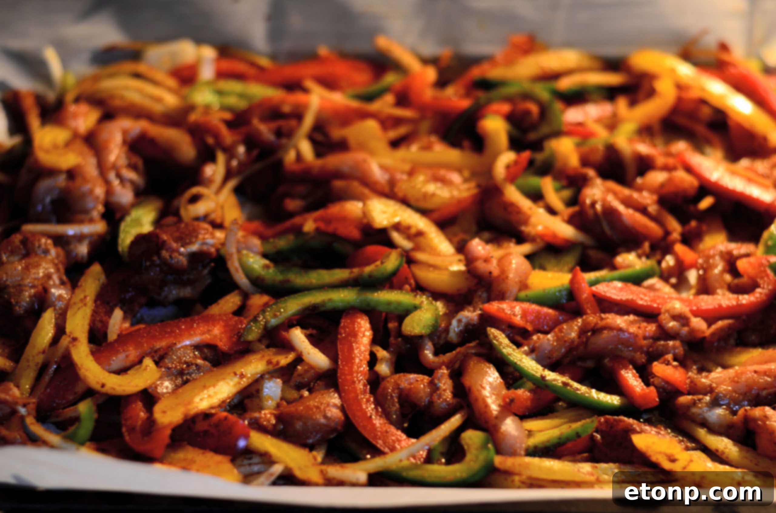Cooked sheet pan chicken fajitas, golden brown and sizzling, served directly on the pan with fresh lime wedges and cilantro.