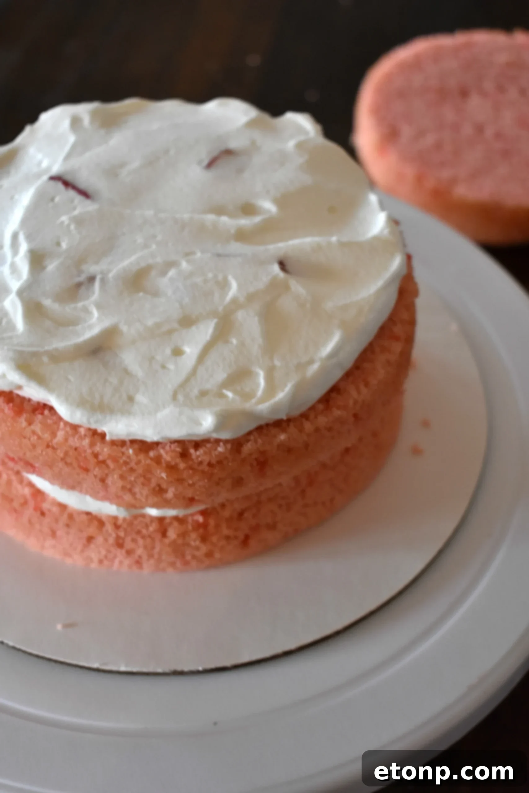 Top-down view of the Strawberry Creamsicle Layered Cake, showcasing its decorative fresh strawberries and a drizzle of sauce.