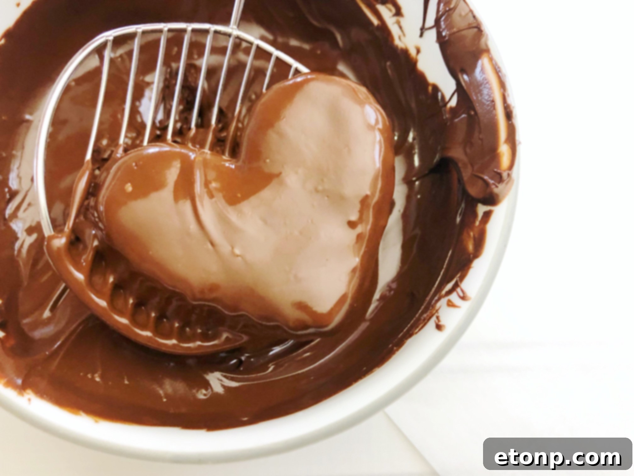 Close-up of three homemade Reese's Peanut Butter Hearts arranged on parchment paper, showcasing their perfect heart shape and rich chocolate coating.