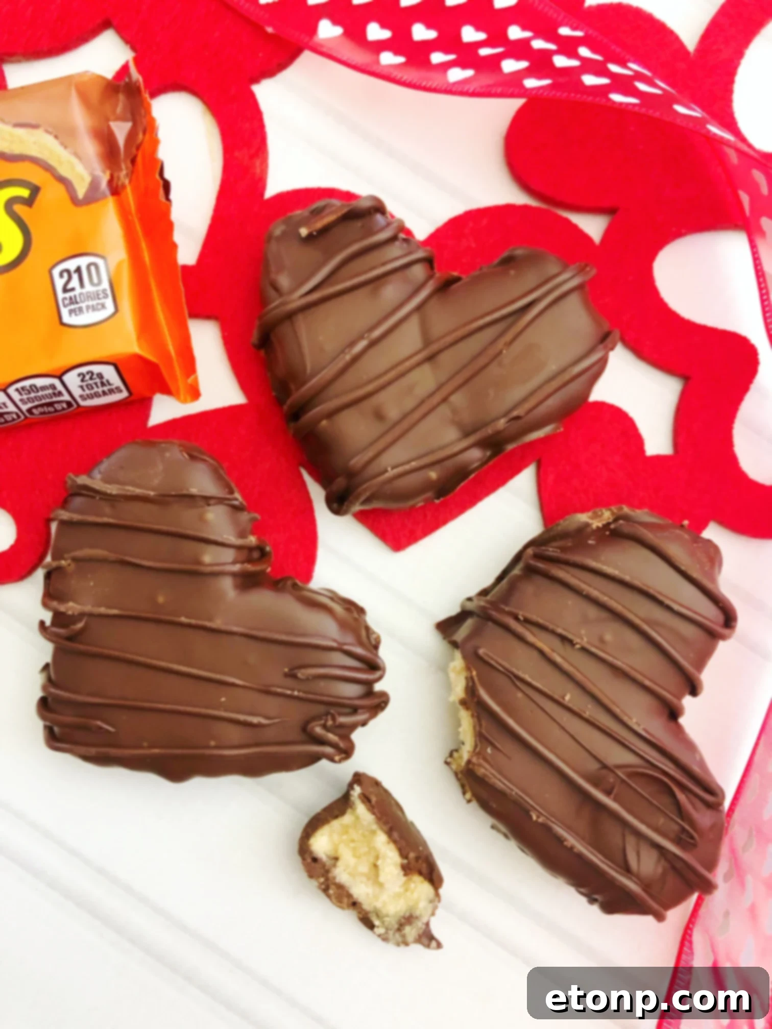 A collection of various cookie cutters, including heart shapes, alongside a rolled-out sheet of peanut butter mixture ready for cutting.