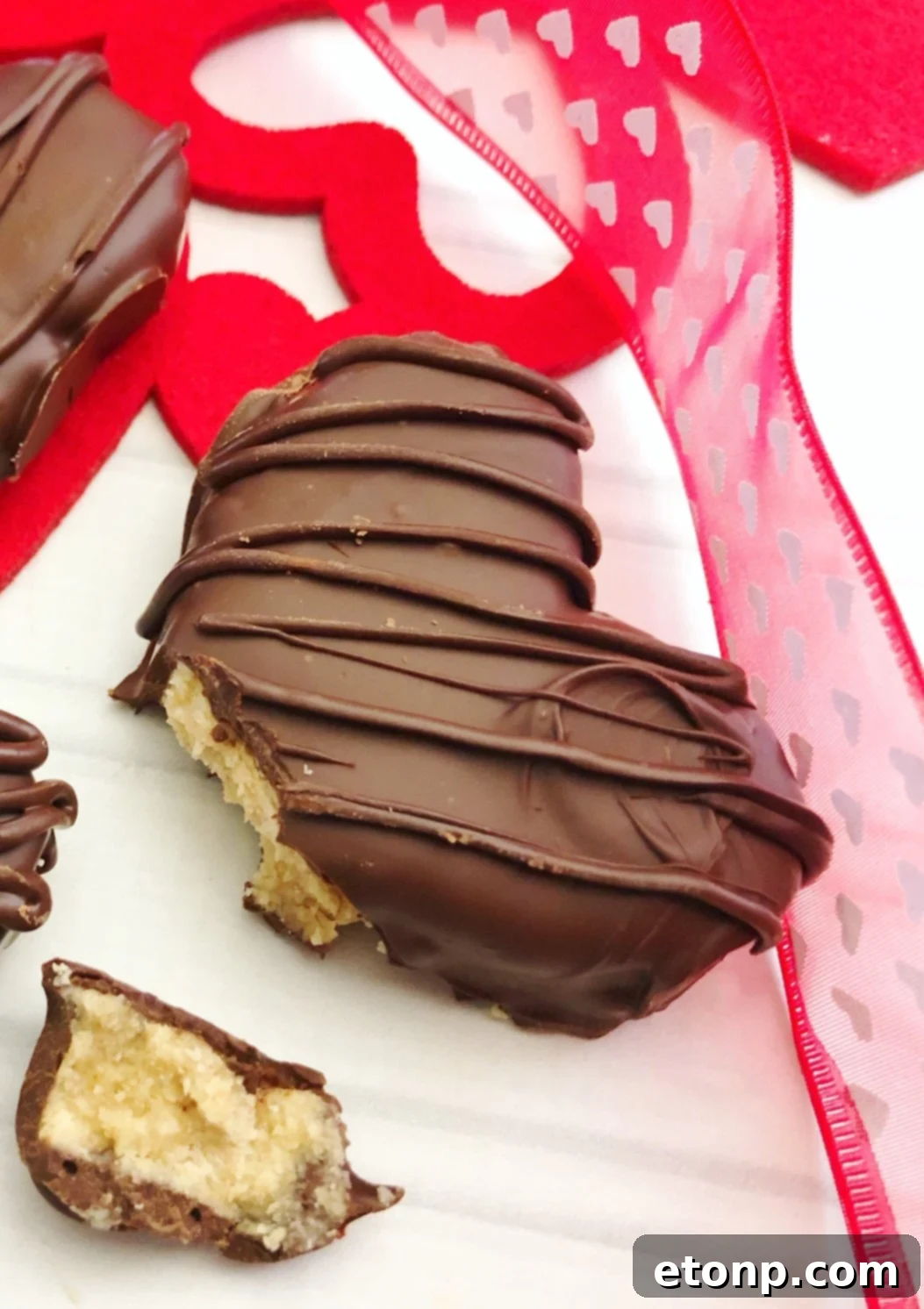 Several homemade Reese's Peanut Butter Hearts arranged on a plate, some with chocolate drizzle, showcasing their festive and delicious appearance.