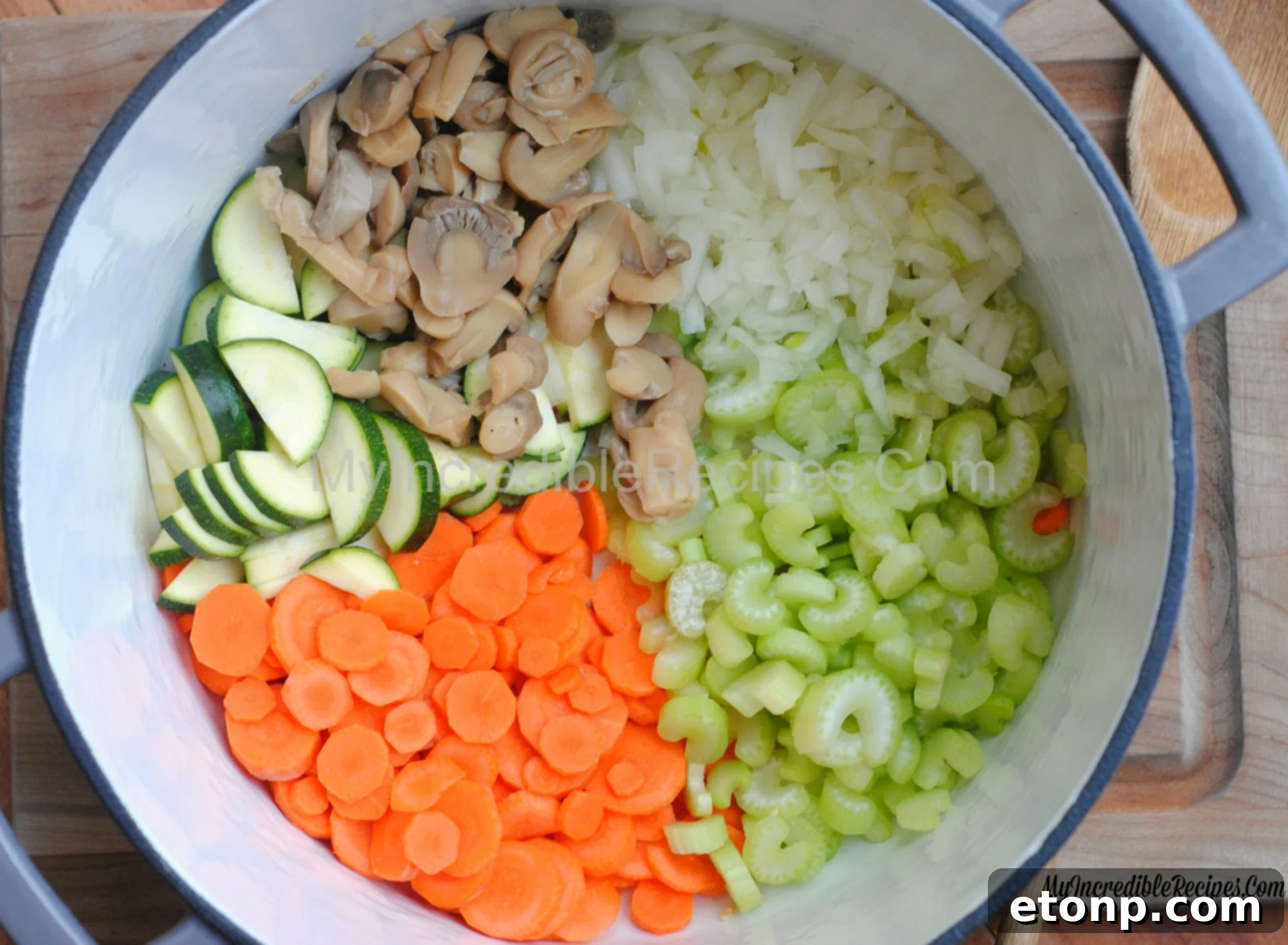 A vibrant selection of fresh ingredients including carrots, celery, zucchini, and an onion, prepared for making healthy soup.