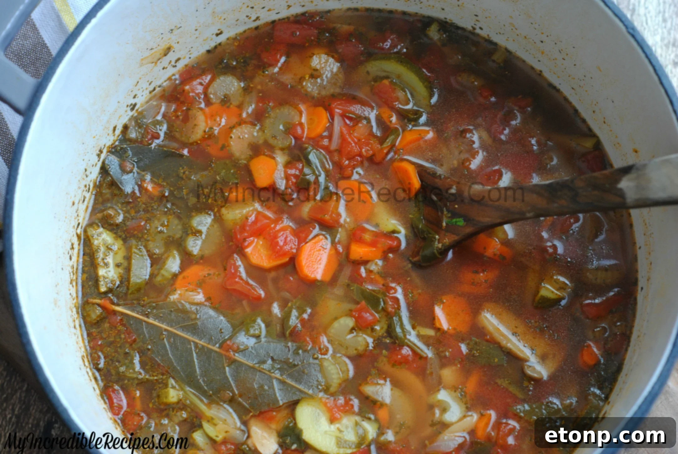 A generous serving of homemade chicken and vegetable soup in a white bowl, accompanied by a small plate of bread.