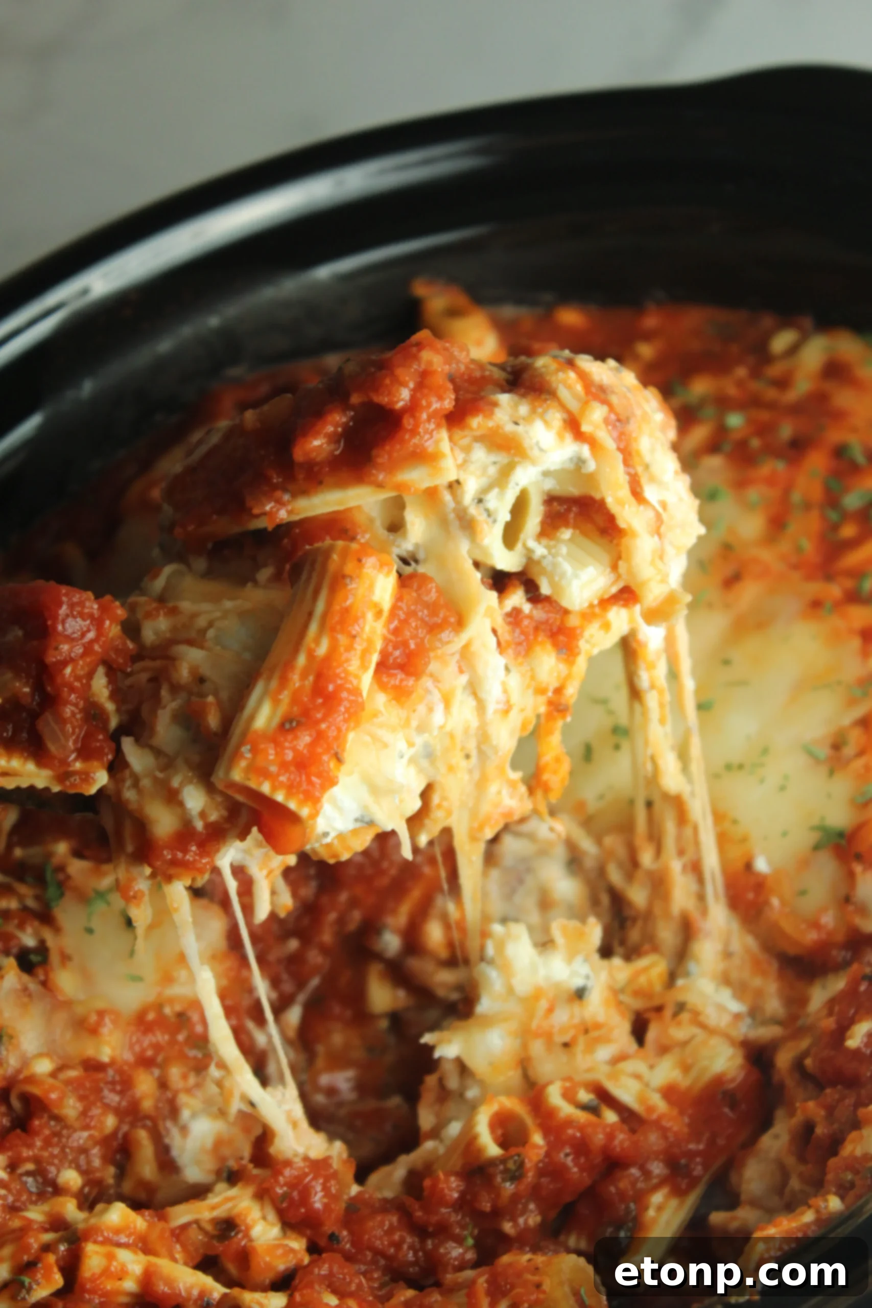 Set It and Forget It Cheesy Baked Ziti 2 A large pot of Slow Cooker Cheesy Baked Ziti, steaming and topped with melted cheese and fresh basil, ready to be served.
