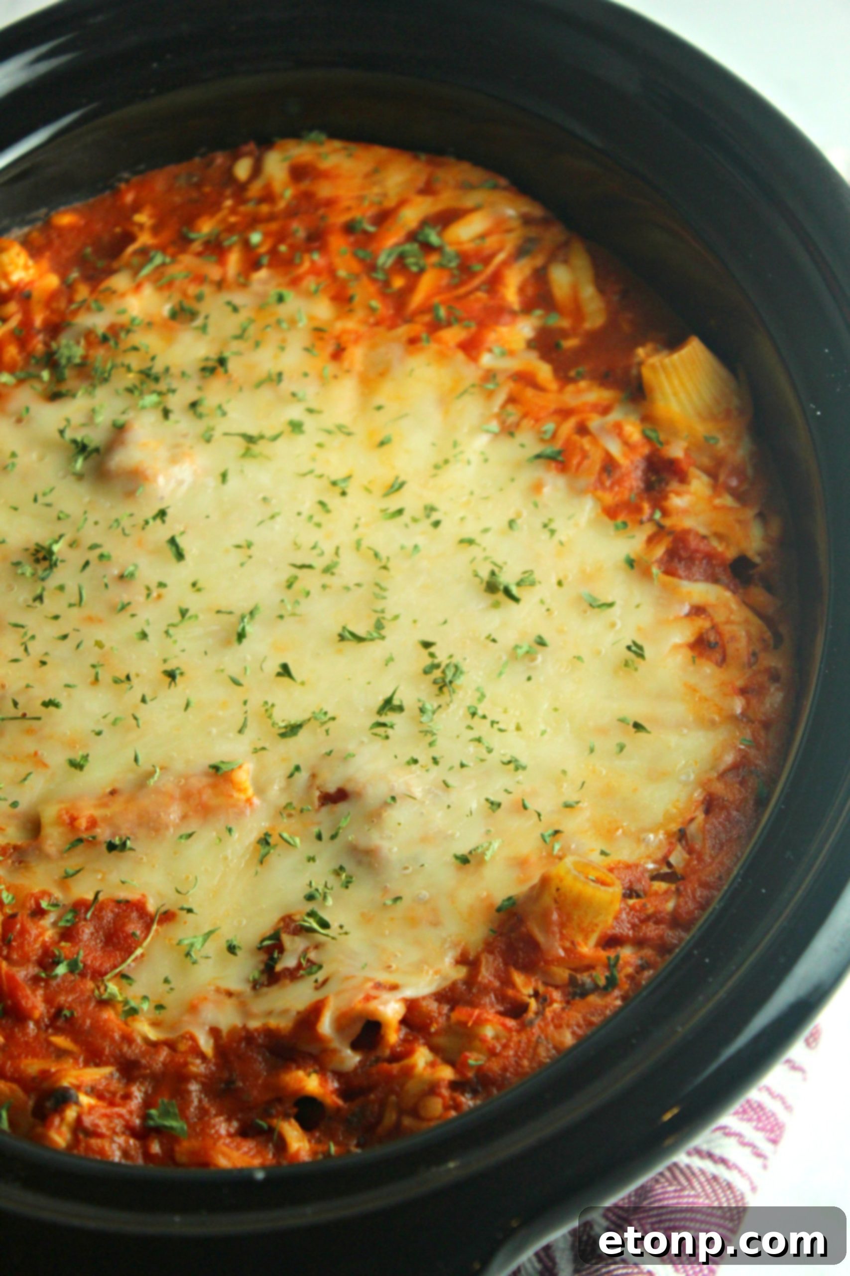 Set It and Forget It Cheesy Baked Ziti 7 A close-up shot of the melted mozzarella and Parmesan cheese topping the baked ziti, creating a golden, bubbly crust.