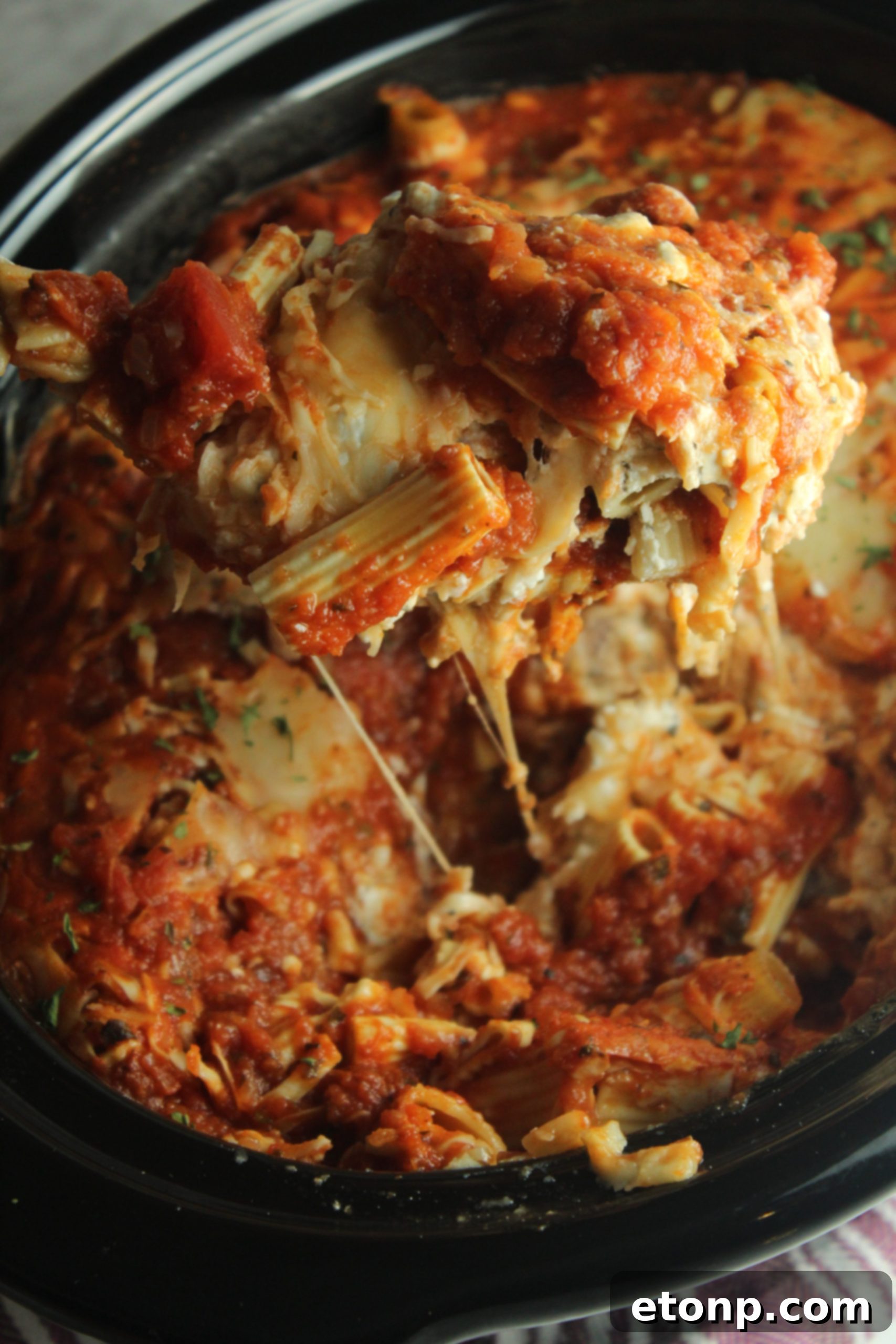 Set It and Forget It Cheesy Baked Ziti 8 A generous serving of Slow Cooker Cheesy Baked Ziti on a white plate, showcasing the layers of pasta, meat, and melted cheese.