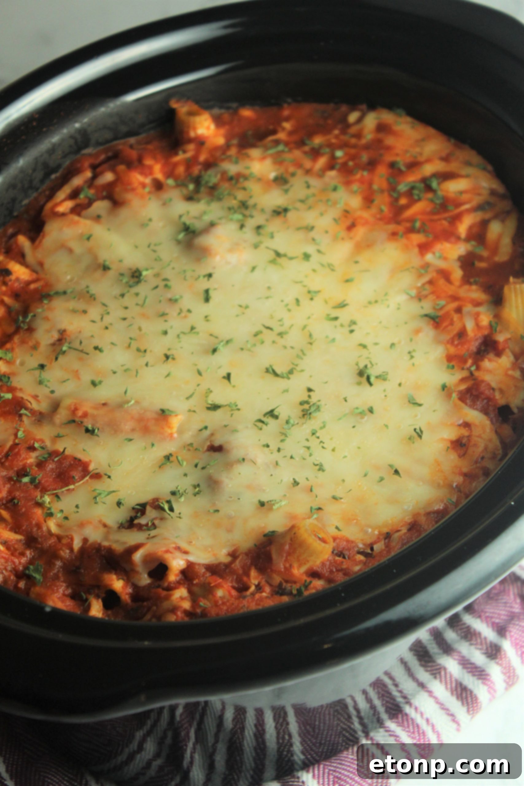Set It and Forget It Cheesy Baked Ziti 9 An overhead shot of the Slow Cooker Cheesy Baked Ziti, showcasing the generous layer of melted cheese and fresh basil garnish.