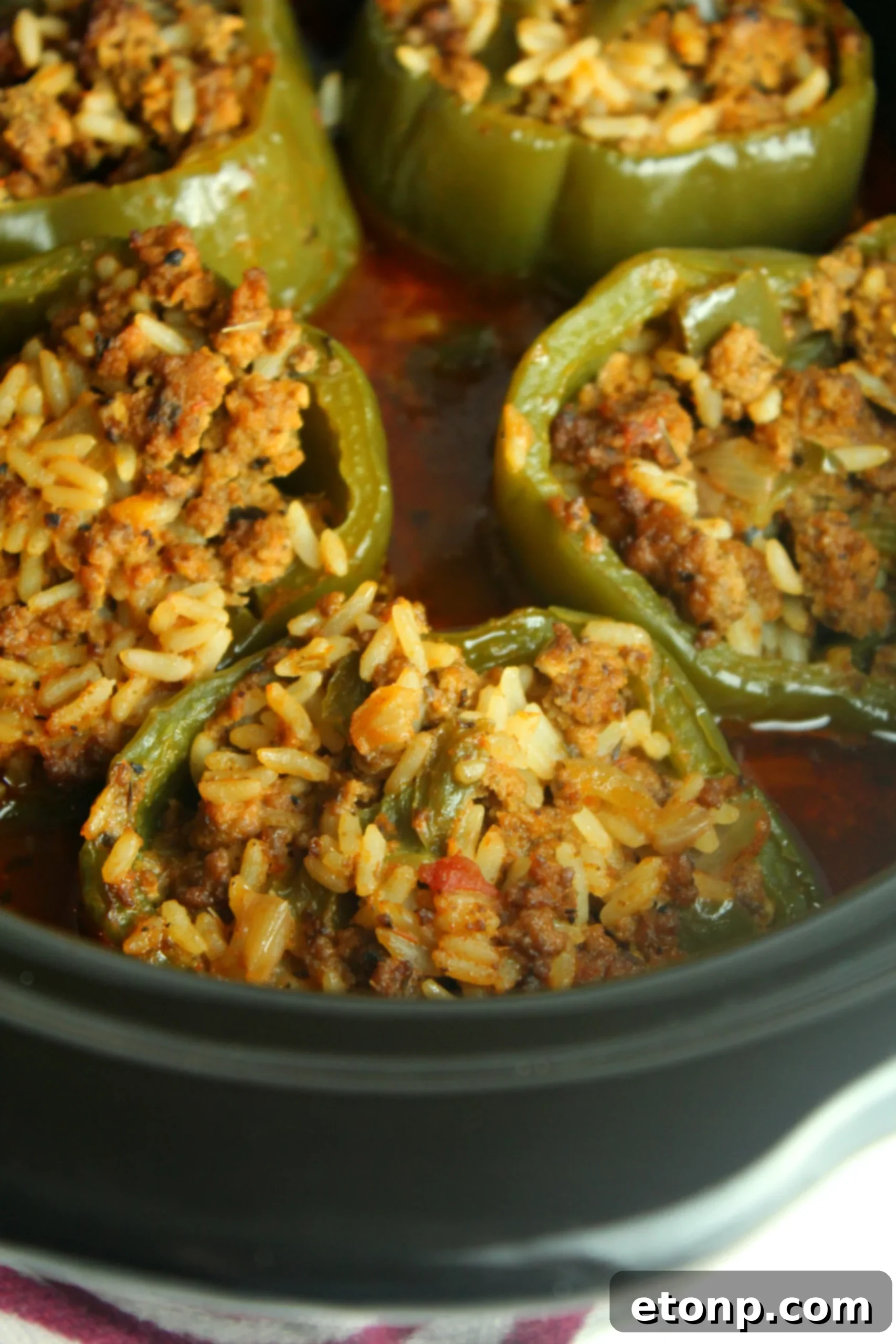 Effortless Slow Cooker Stuffed Peppers 2 A vibrant red bell pepper stuffed with savory ground beef and rice mixture, resting on a bed of tomato sauce in a slow cooker.