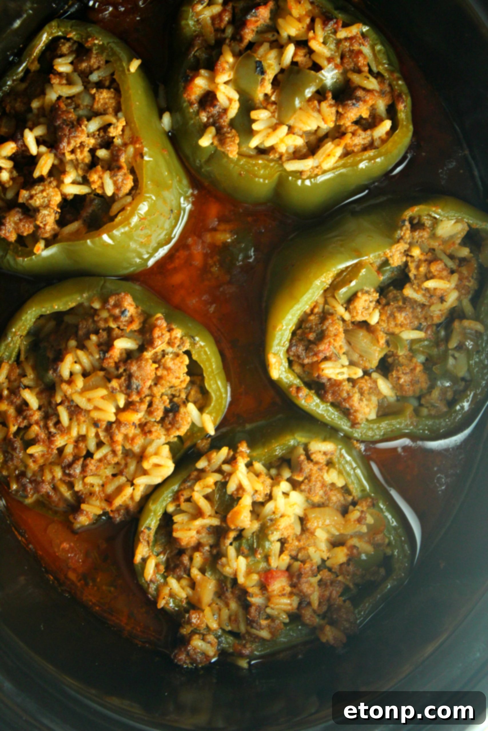 Effortless Slow Cooker Stuffed Peppers 3 Two halves of a stuffed bell pepper, showcasing the rich, meaty filling and tender texture, served on a white plate.