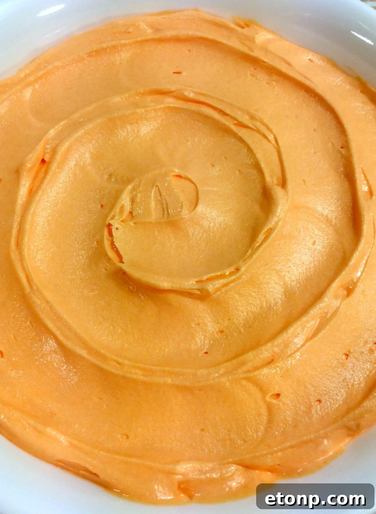 Bright orange creamsicle buttercream frosting piped perfectly on cupcakes.