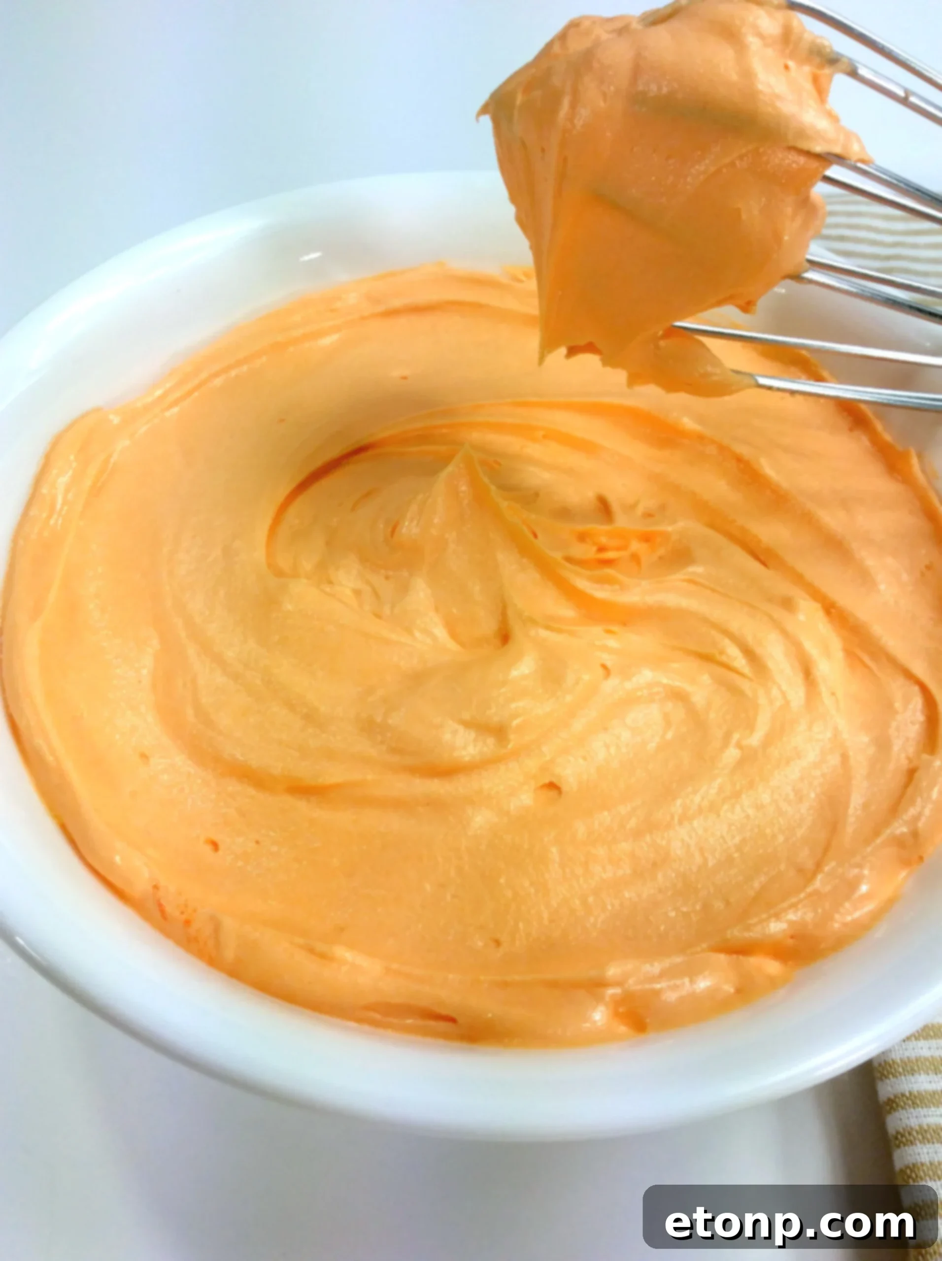 Orange creamsicle buttercream generously applied to a chocolate cupcake.