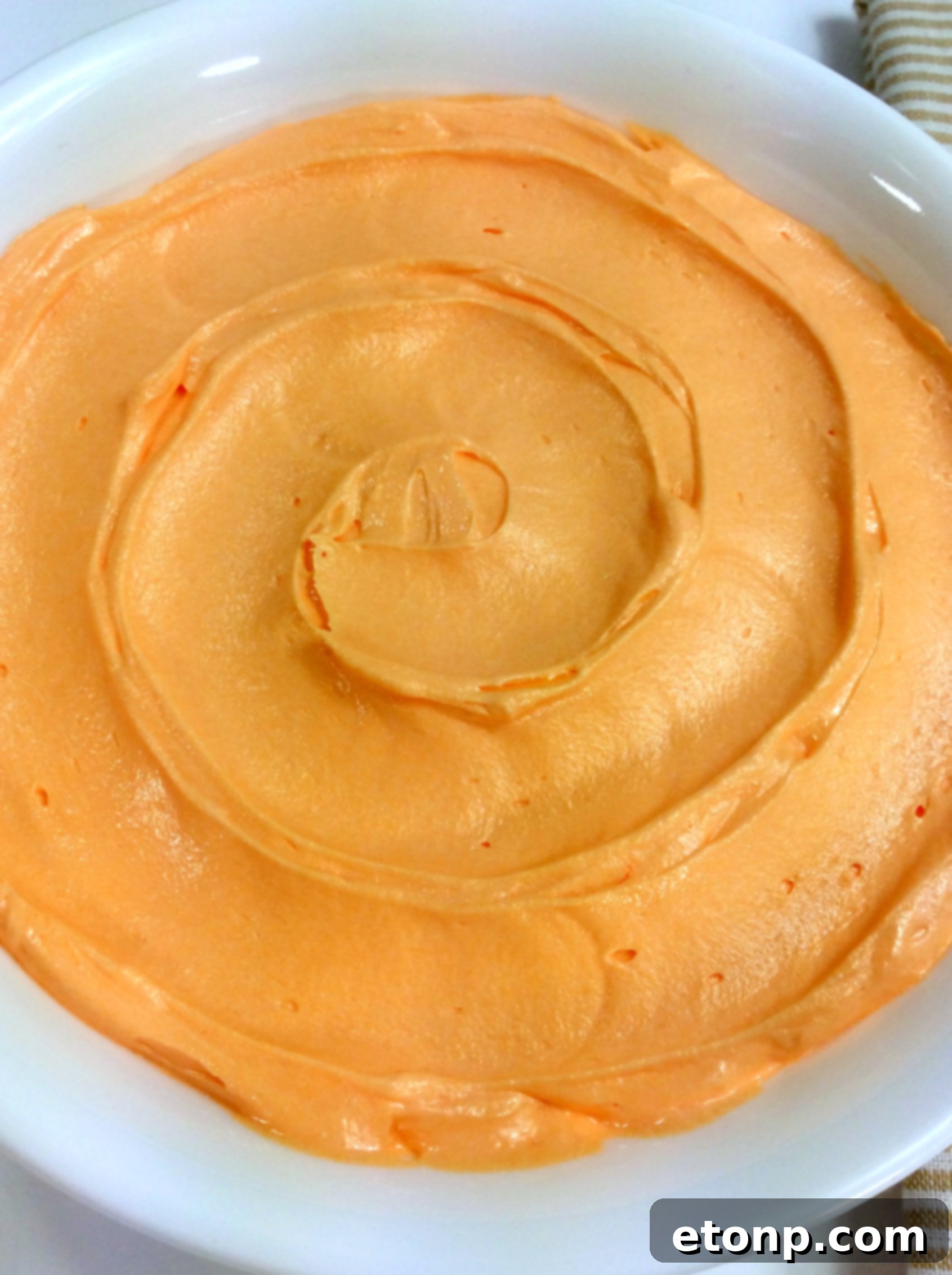 Delicious orange creamsicle frosting piled high on a dessert spoon.