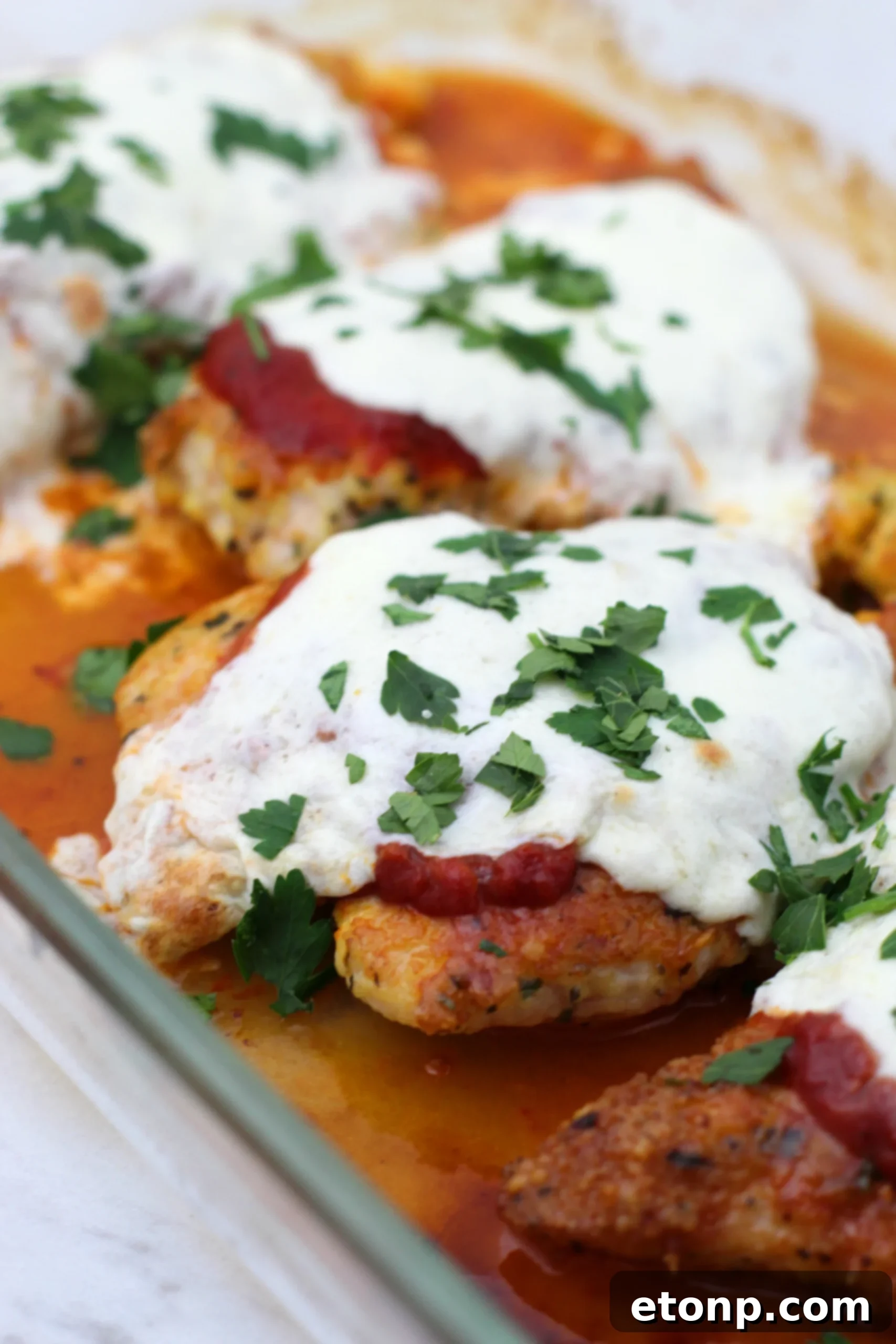 Keto Chicken Parmesan Perfection 2 Perfectly golden-brown Keto Chicken Parmesan with melted mozzarella and fresh basil, ready to be served