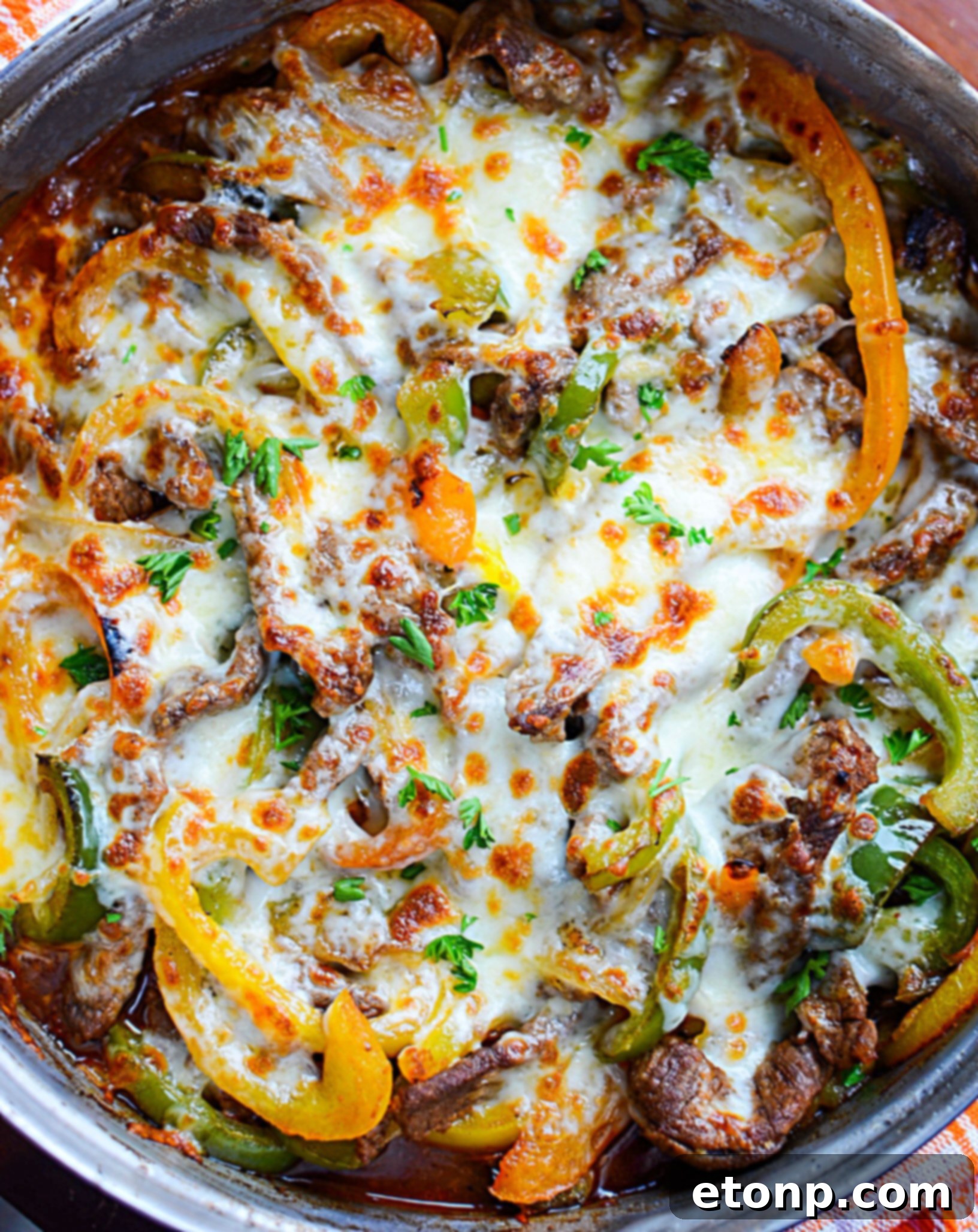 Close-up of a sizzling low carb Philly cheesesteak skillet, featuring thinly sliced steak, melted cheese, and sautéed peppers and onions.