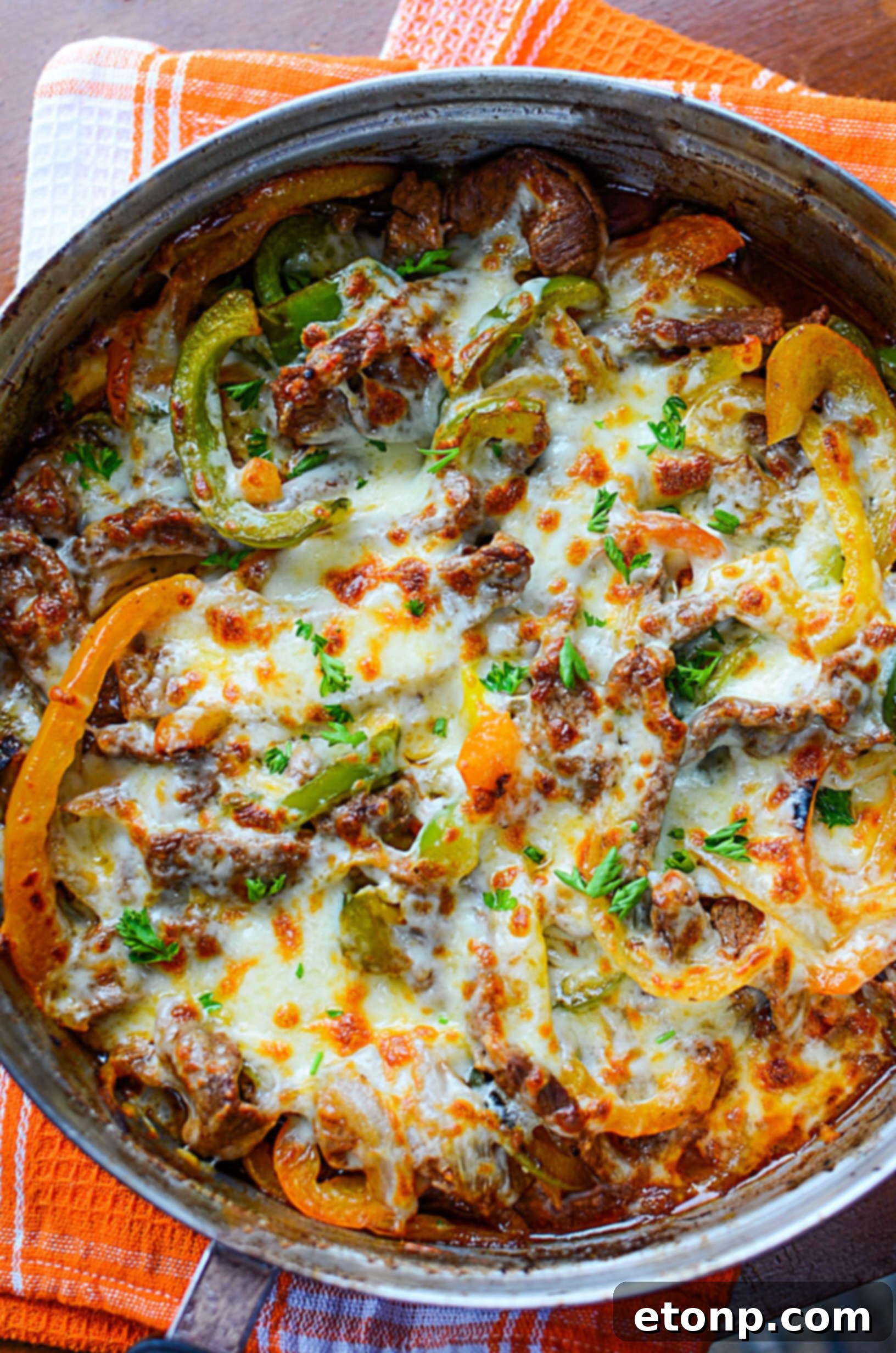 A close-up of the cooked steak, peppers, and onions in the skillet, ready for the cheese.