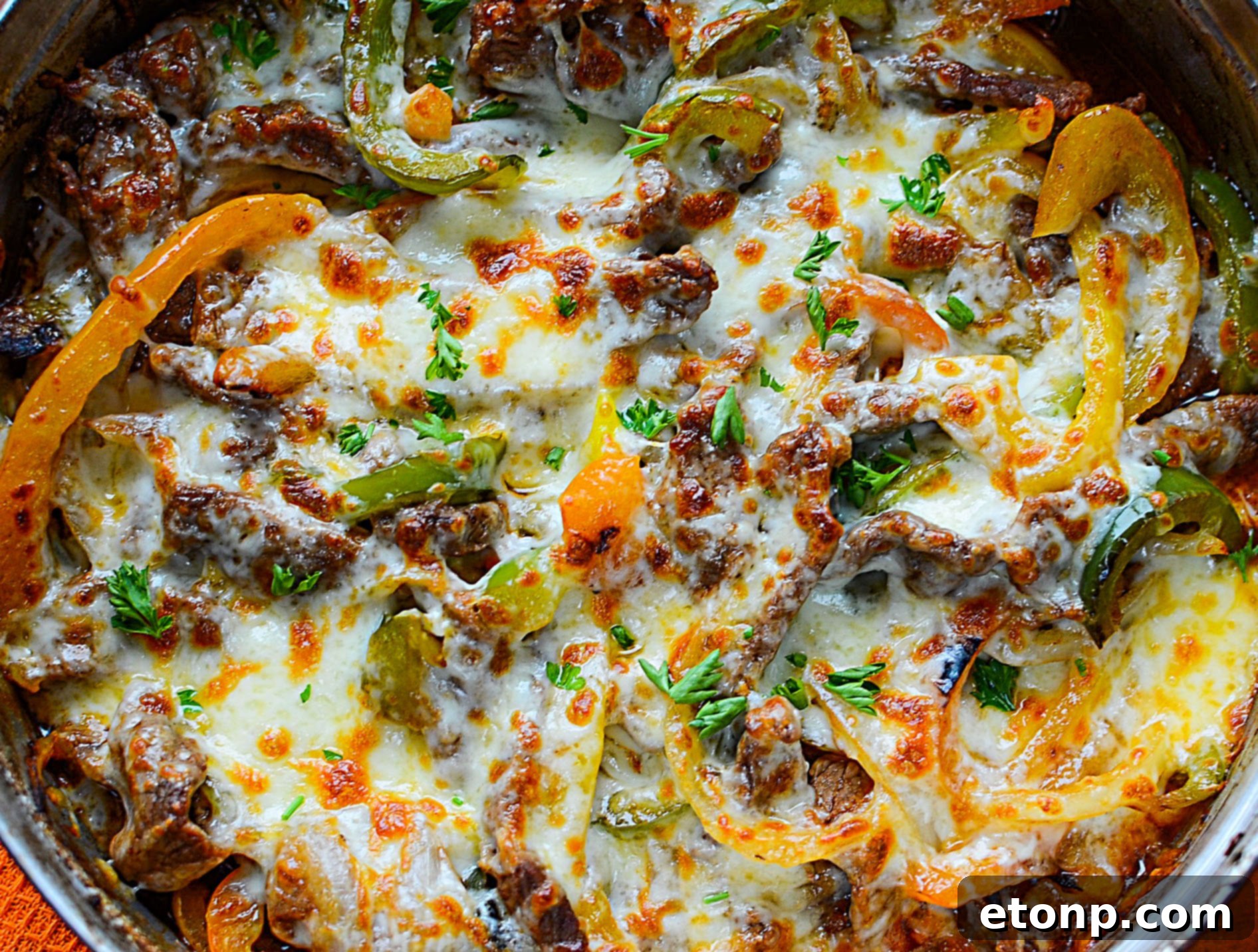 The skillet filled with the combined ingredients: steak, peppers, onions, and melted cheese, making a mouthwatering low carb dish.