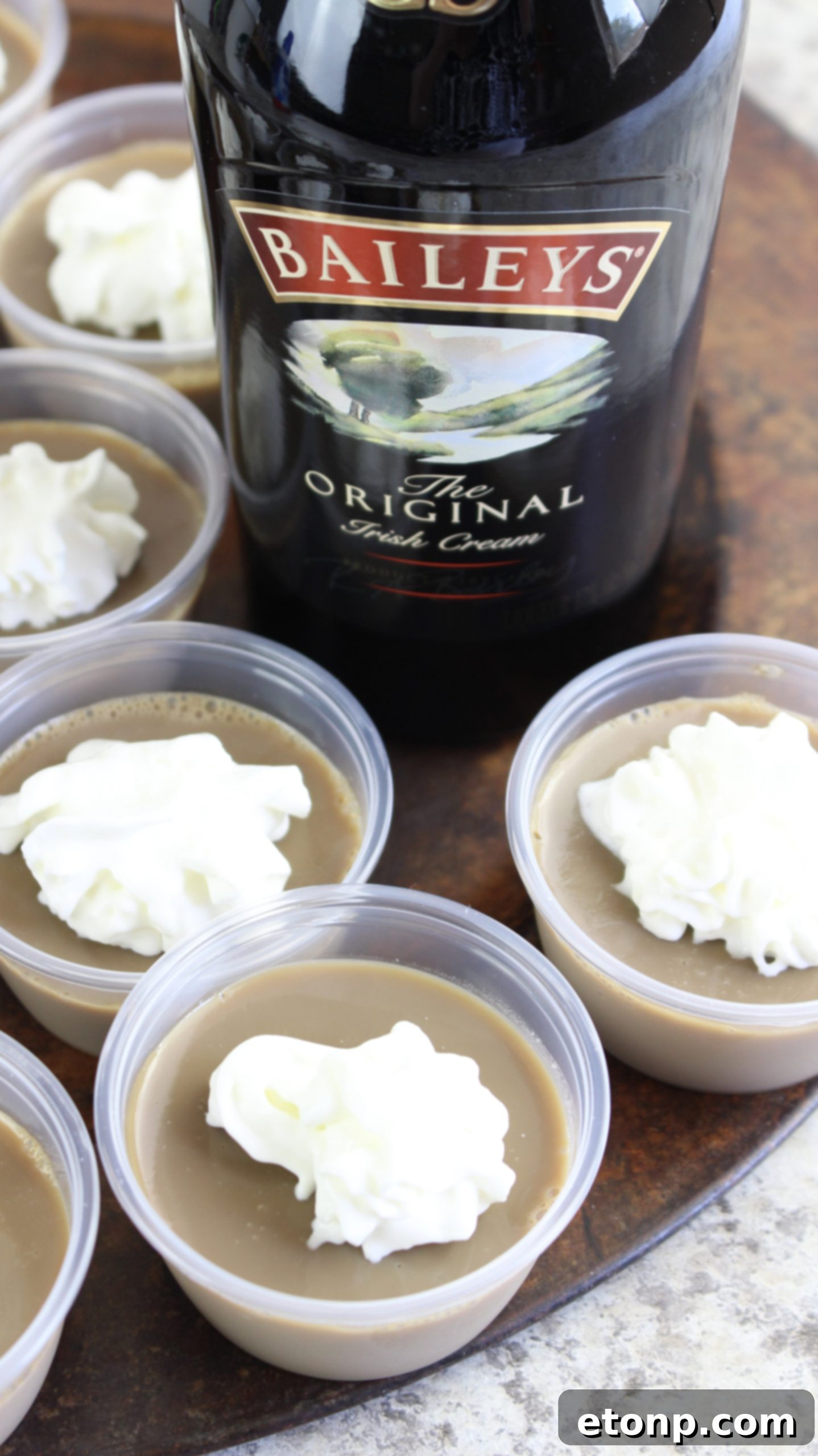 A close-up shot of a single Baileys Irish Cream Jello Shot, perfectly garnished with whipped cream and a cherry.