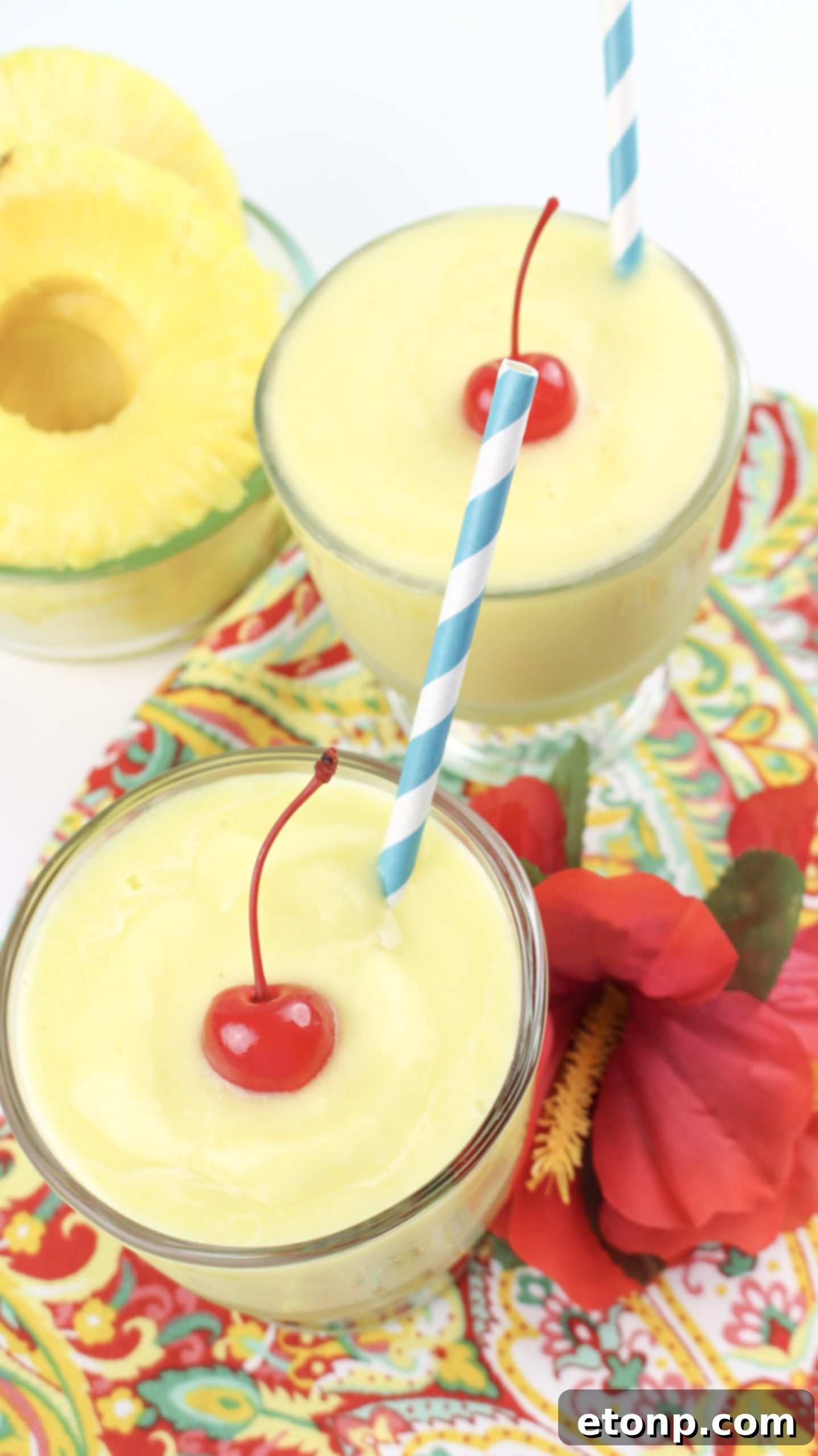 Dole Pineapple Whip in a tall glass, garnished with a maraschino cherry and a slice of fresh pineapple