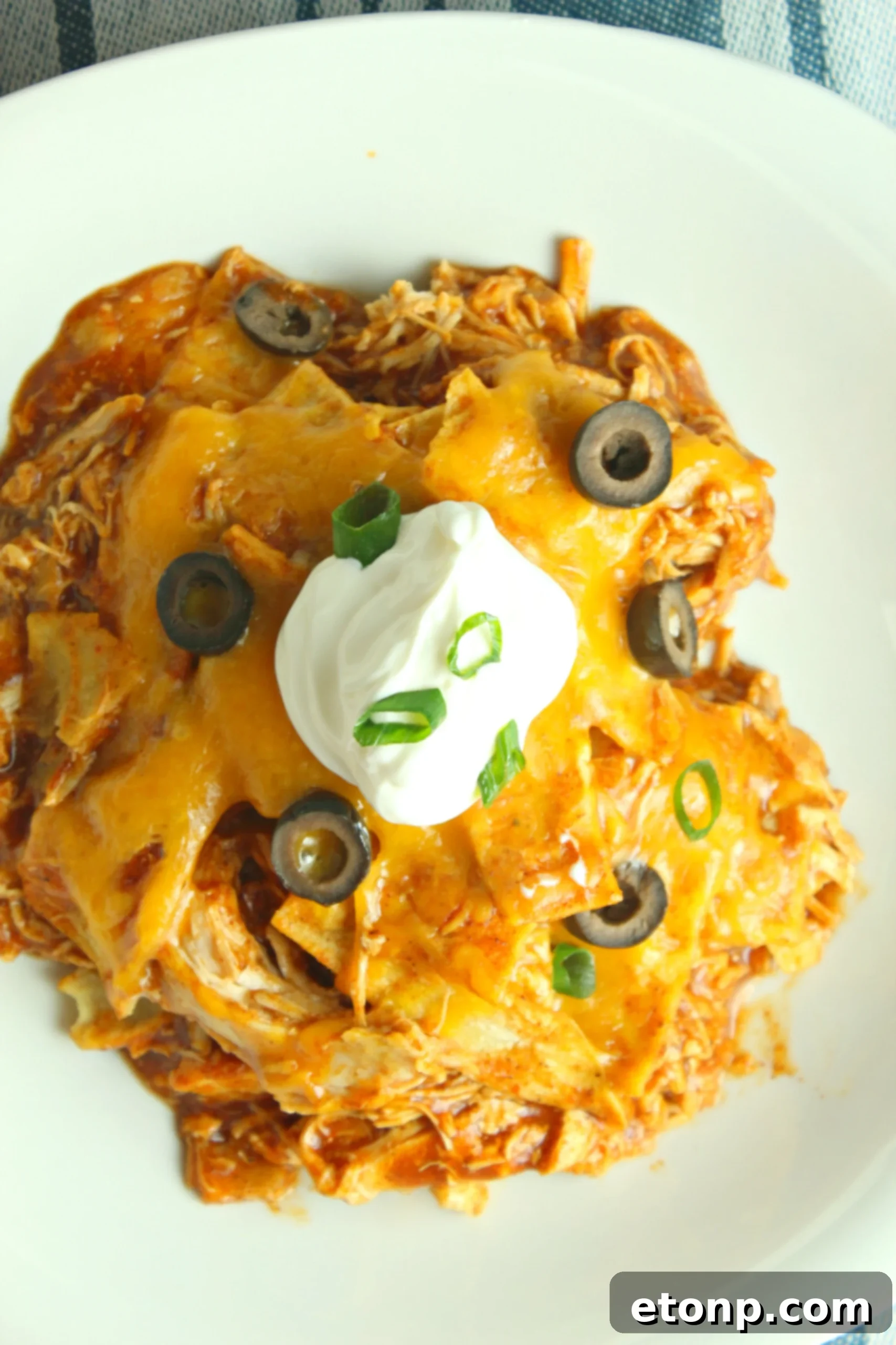 Slow Cooker Chicken Enchilada Casserole layers with juicy chicken, beans, corn, tortillas, and gooey cheese