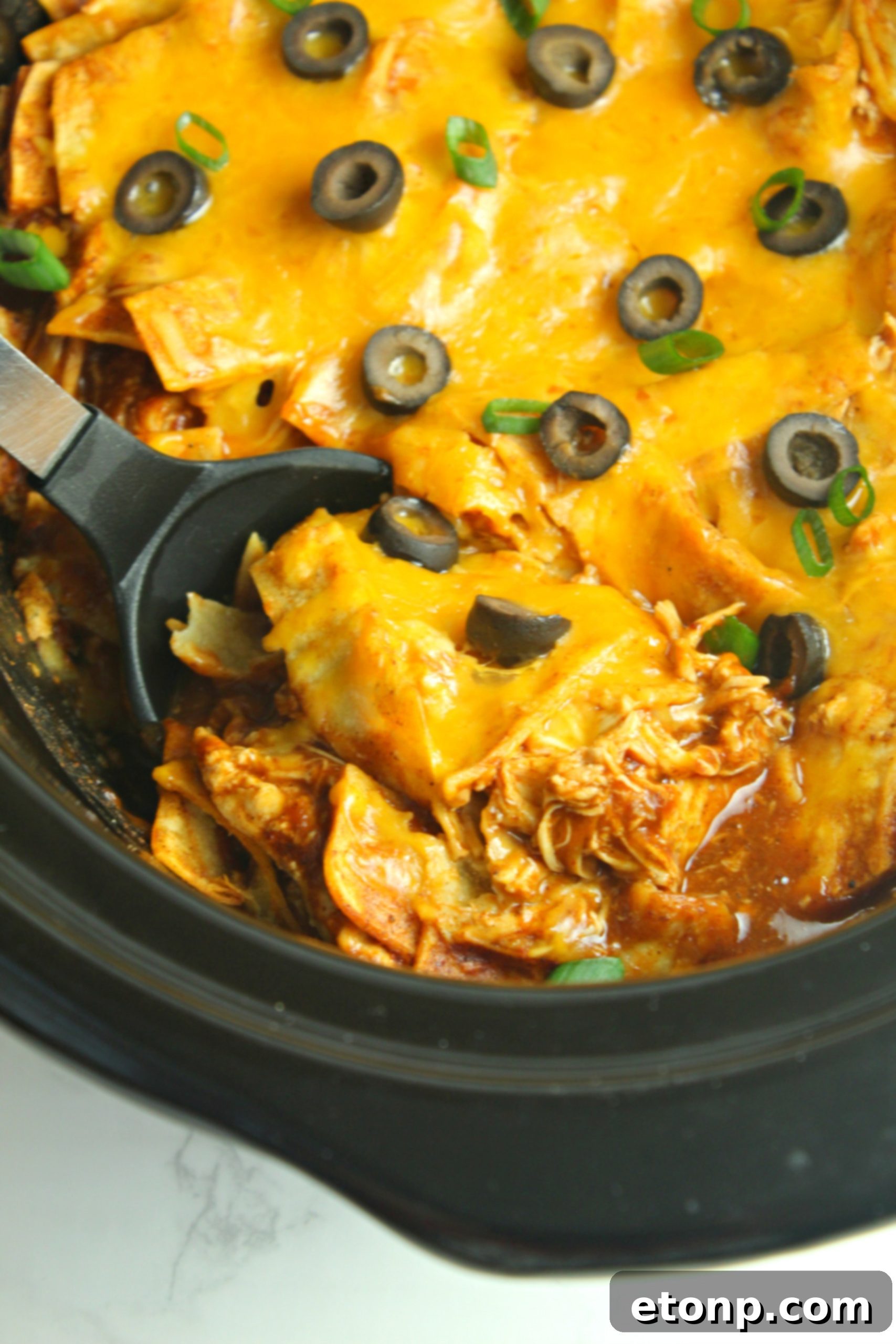 Slow Cooker Chicken Enchilada Casserole bubbling hot with melted cheese and olives, ready to serve