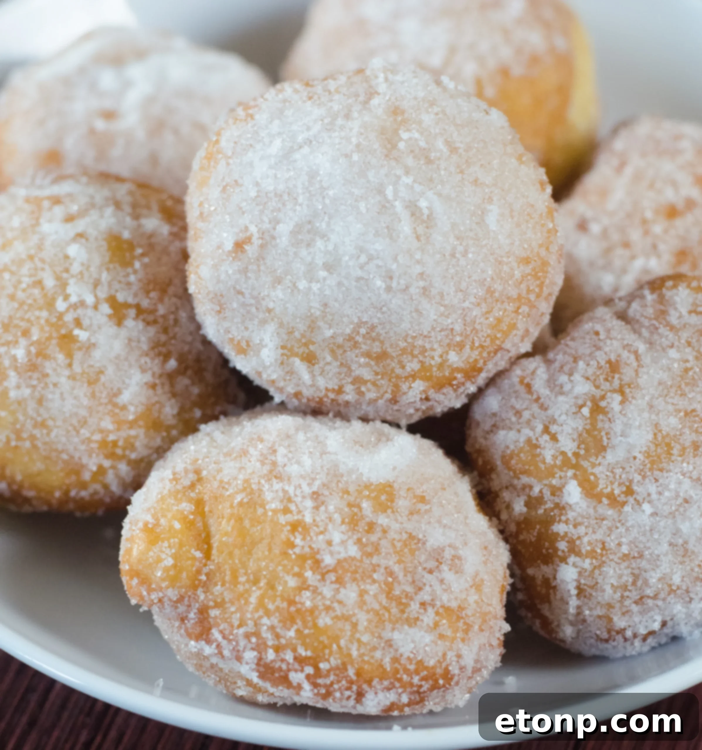 A freshly made, golden brown Chinese sugar donut, glistening with sugar crystals, set against a warm background.