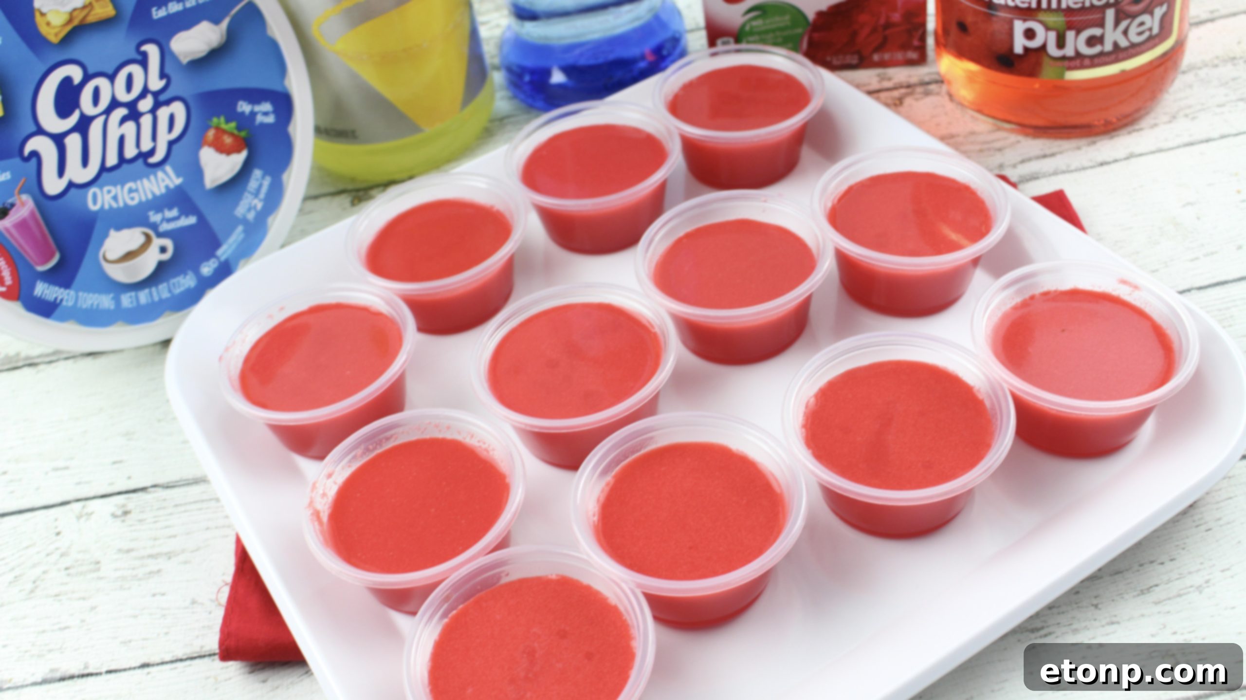 Cherry Starburst Jiggle Pops 4 Overhead shot of several Cherry Starburst JELL-O Shots arranged neatly, highlighting their appealing presentation with whipped cream and candy garnishes.