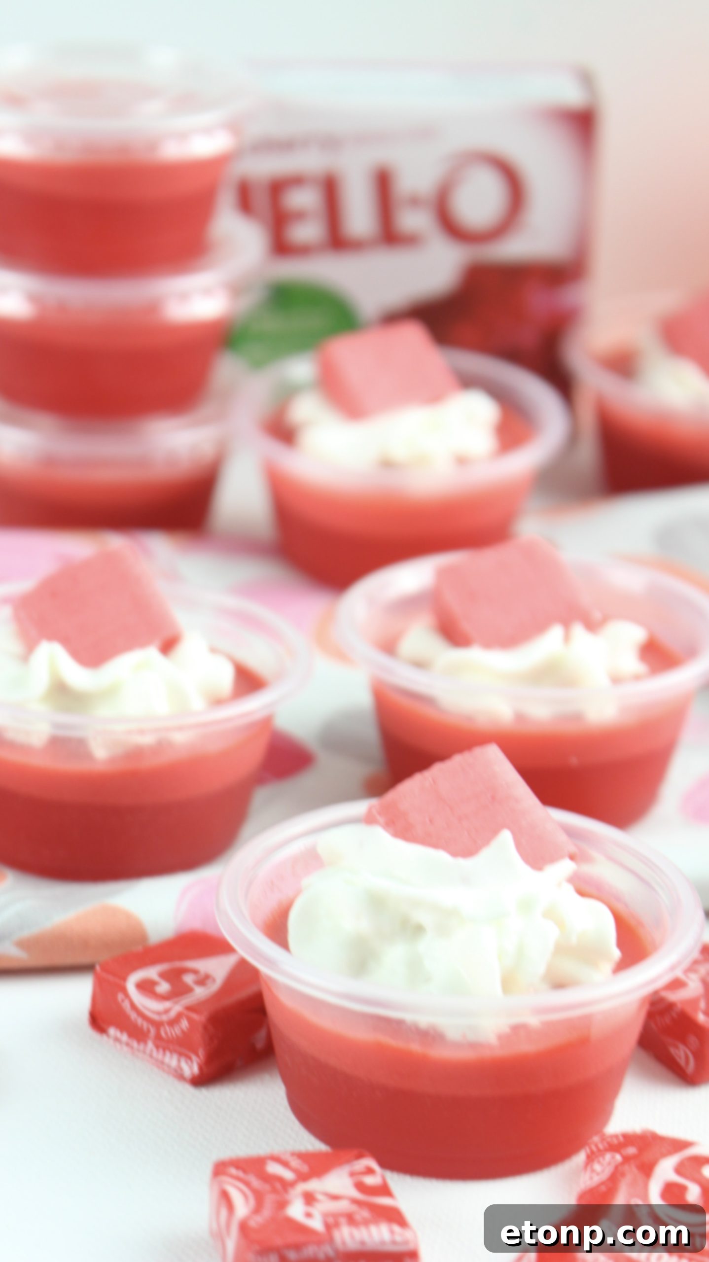 Cherry Starburst Jiggle Pops 8 A close-up of various JELL-O shots, some with whipped cream and candy garnishes, showing the detail and appeal of each individual shot.