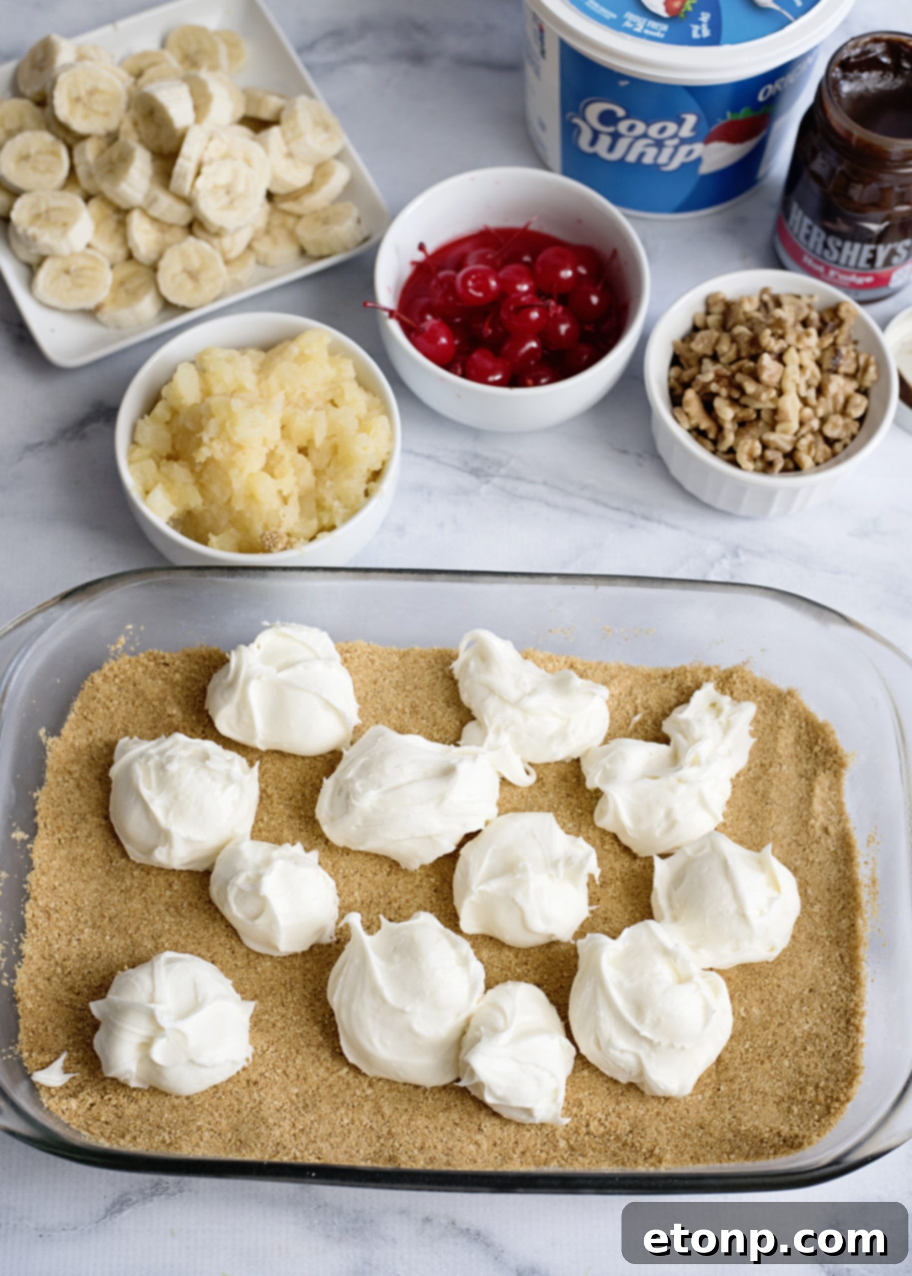 Overhead view of a slice of No-Bake Banana Split Dessert with hot fudge drizzle and cherry on top
