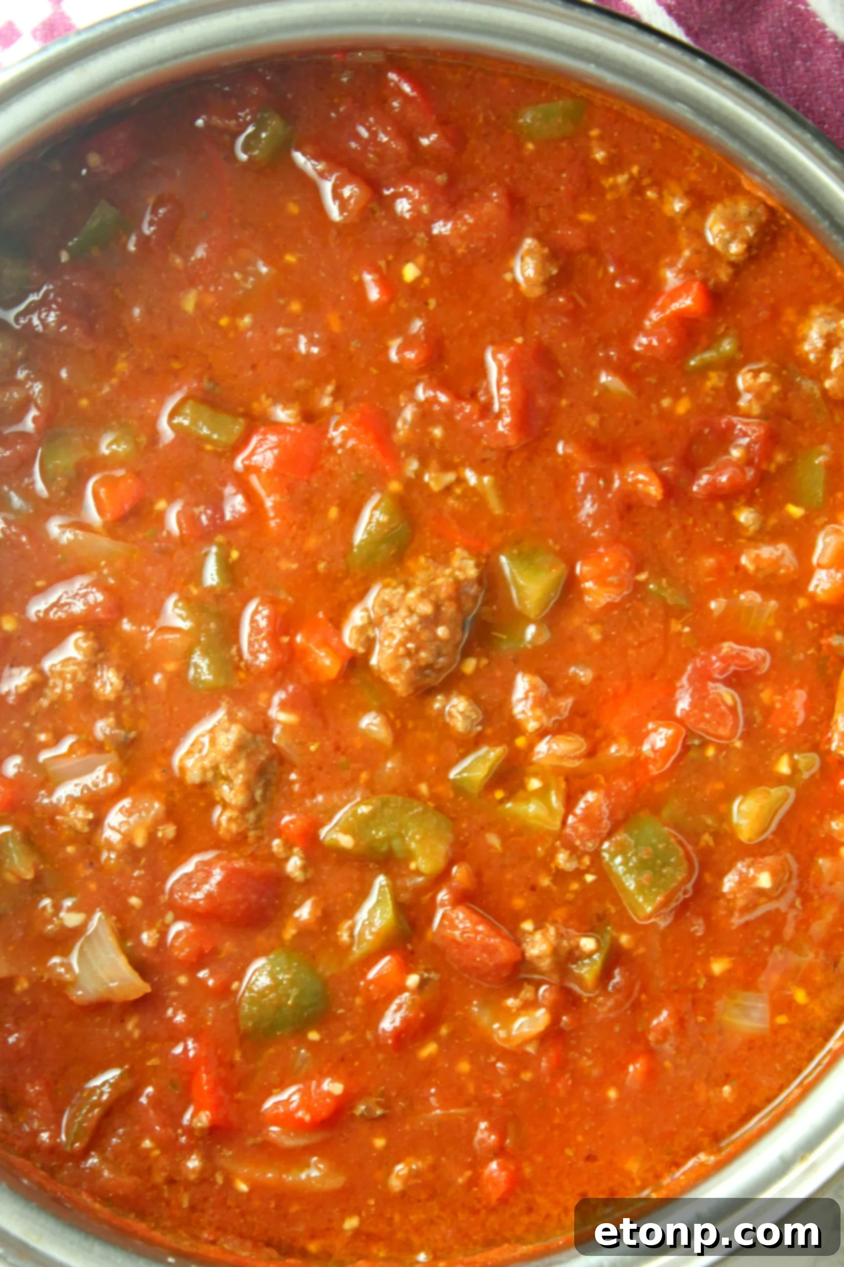 Homestyle Stuffed Pepper Stew 5 Ingredients for hearty stuffed pepper soup laid out on a cutting board, including bell peppers, onion, and ground meat.