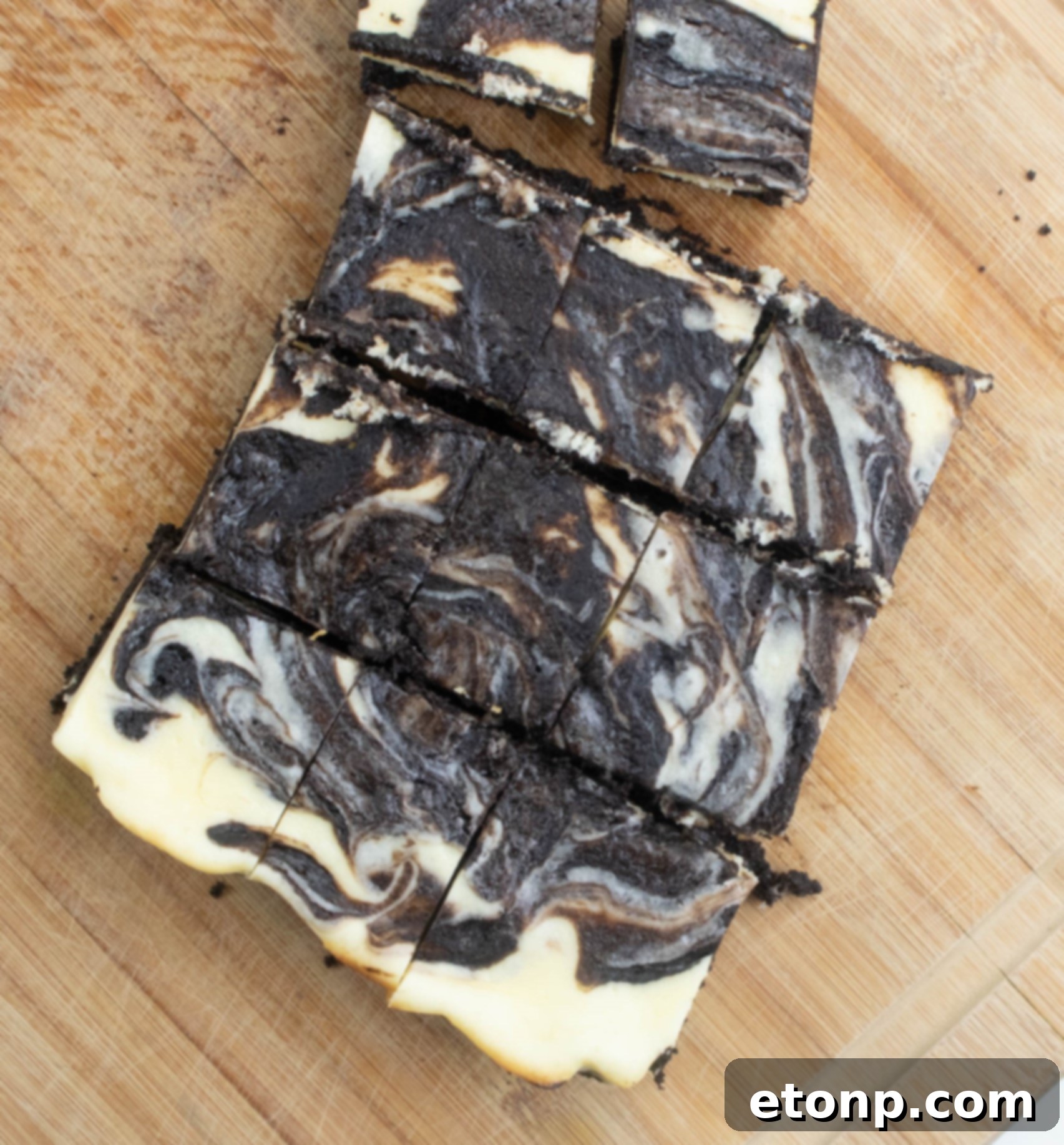 Homemade Cheesecake Swirl Brownies 4 Freshly baked cheesecake swirl brownies cooling in a pan, ready to be cut into individual servings.