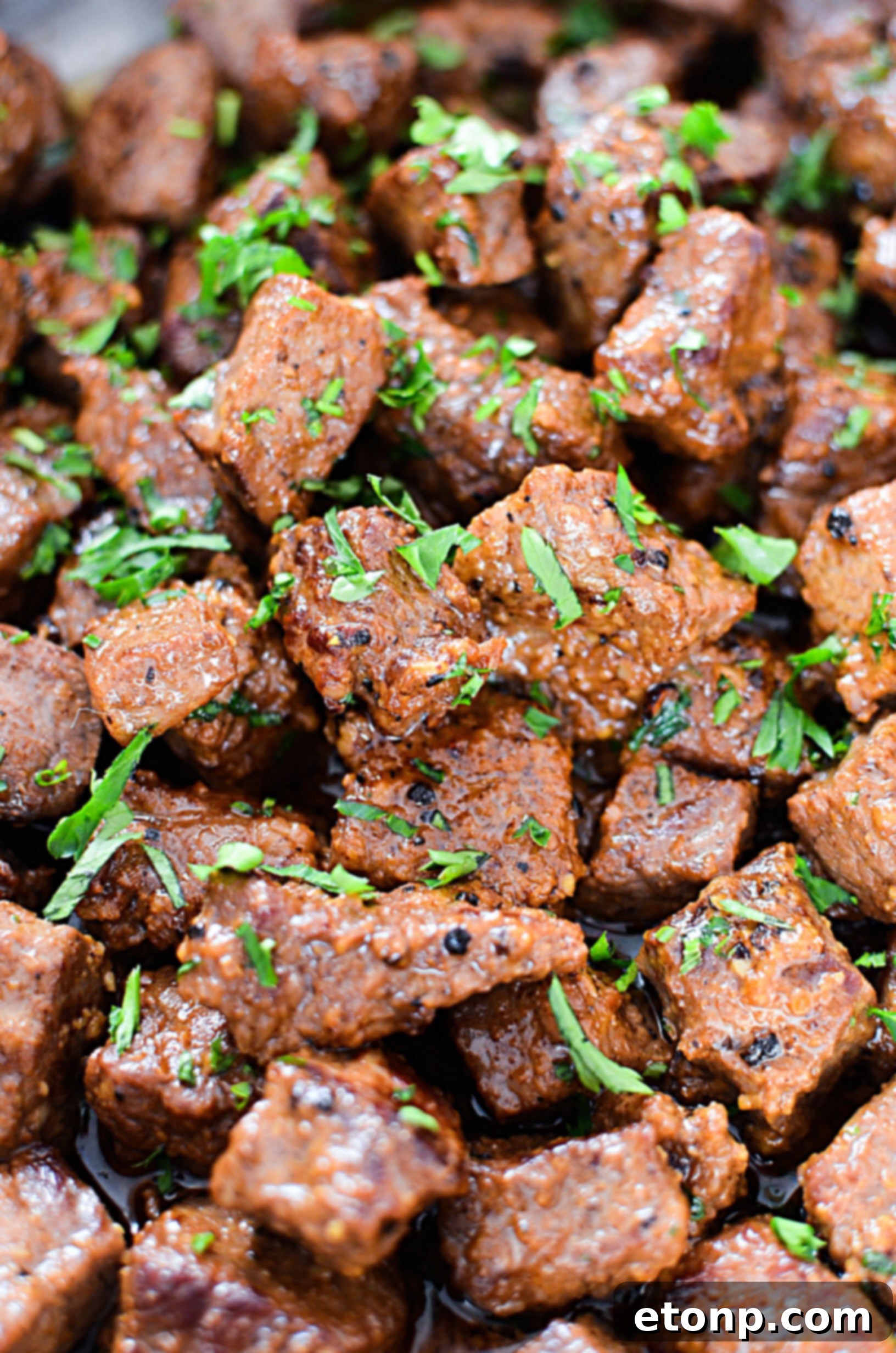 Close-up of golden-brown garlic butter steak bites in a skillet, garnished with fresh parsley.